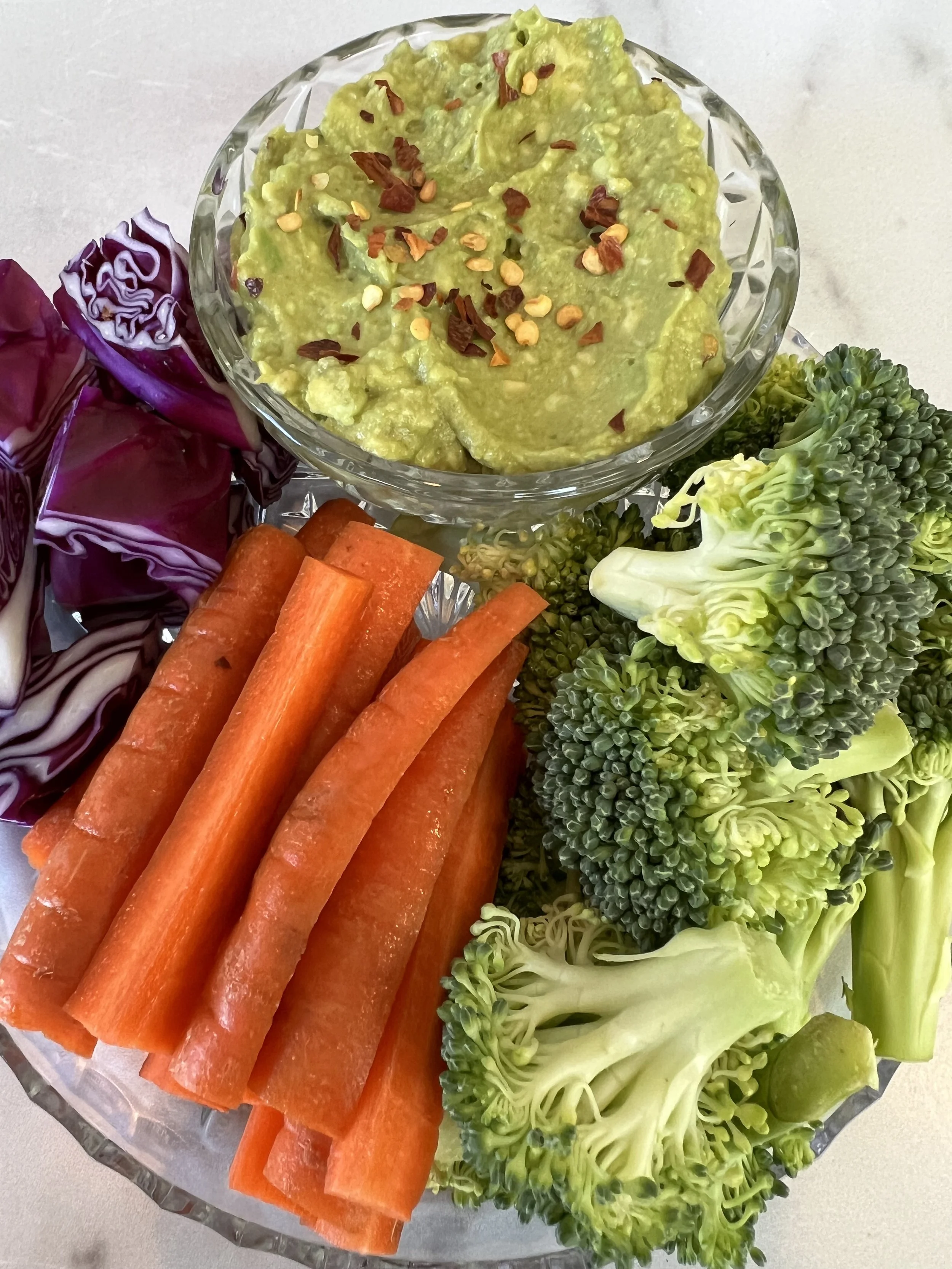 Raw Broccoli, red cabbage, and carrots served with guacamole.