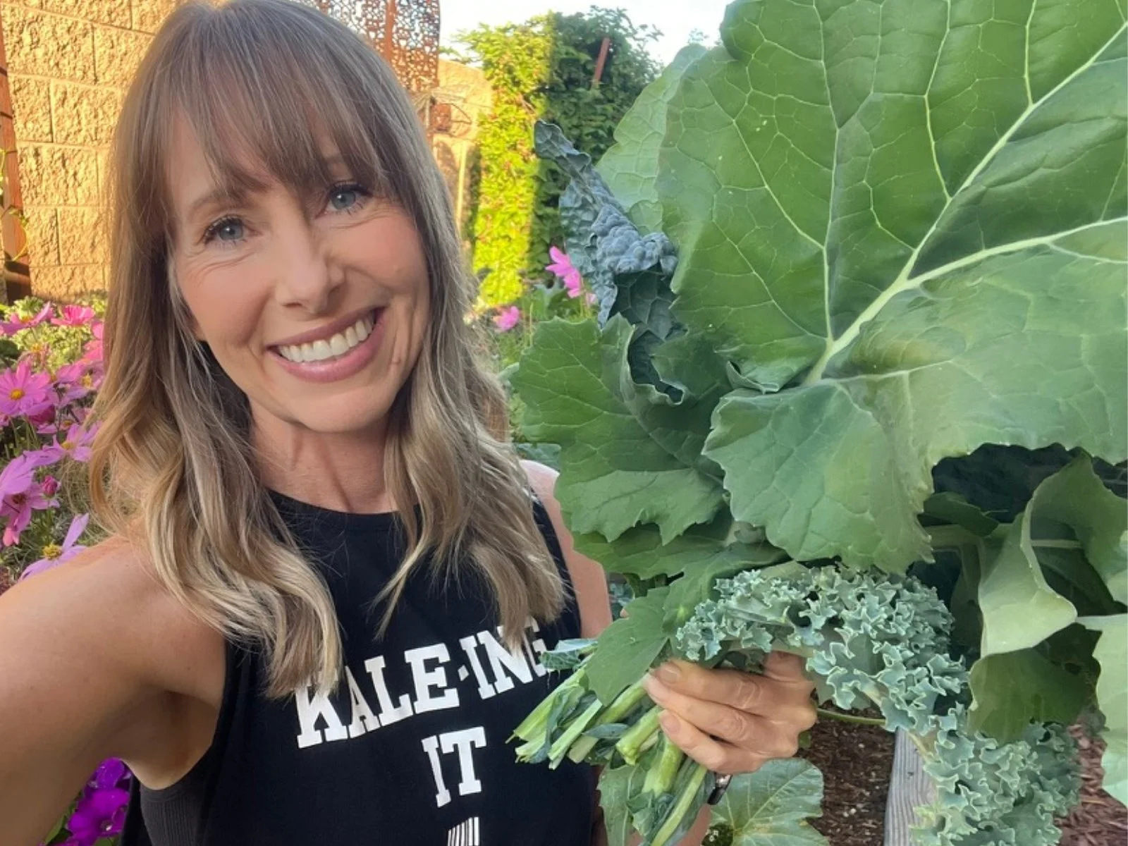 Green Food Crush creator Michelle holding freshly harvested kale in her vegetable garden