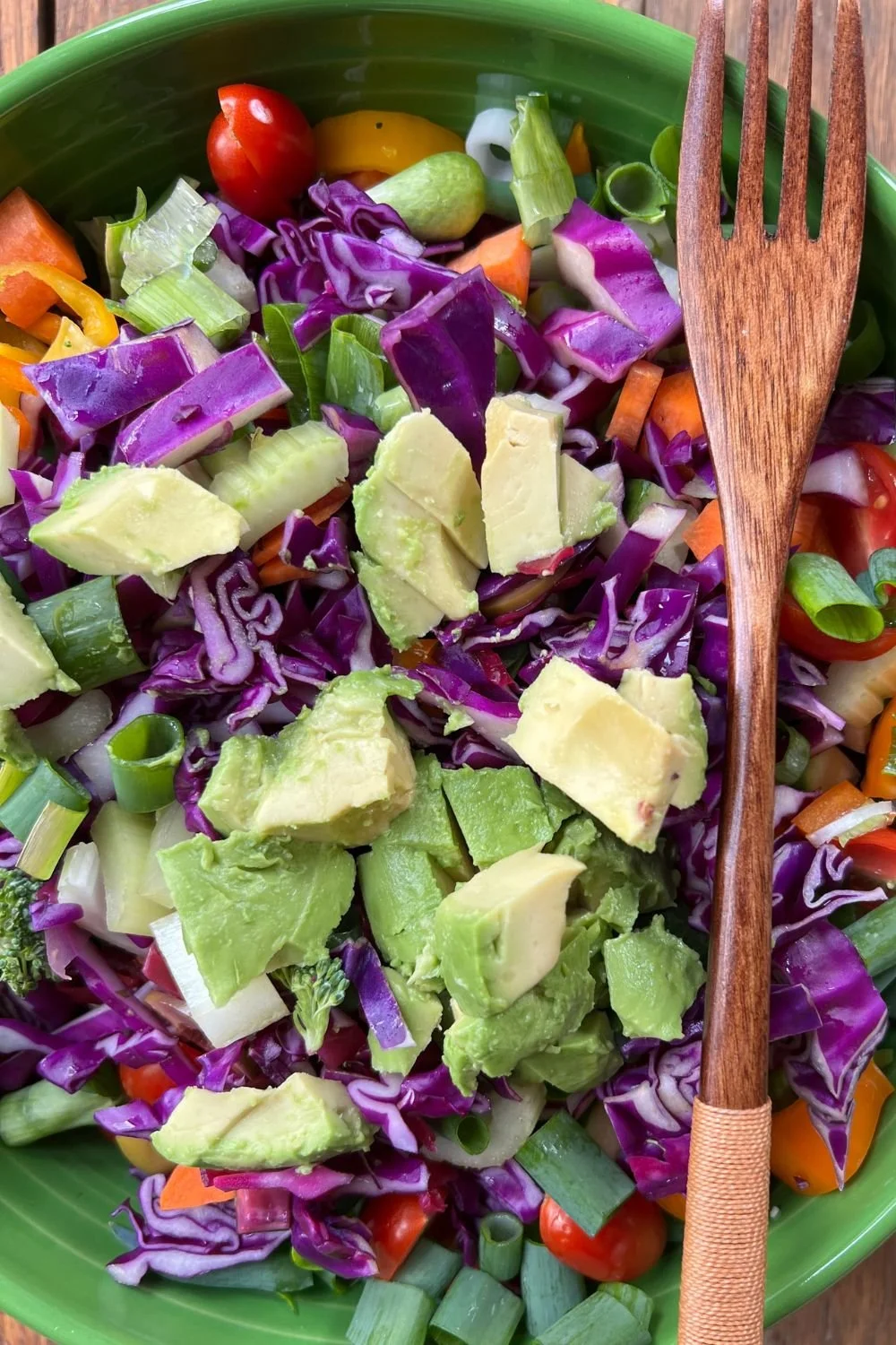 Colorful raw red cabbage salad with avocado, cucumber, peppers, and green onions.