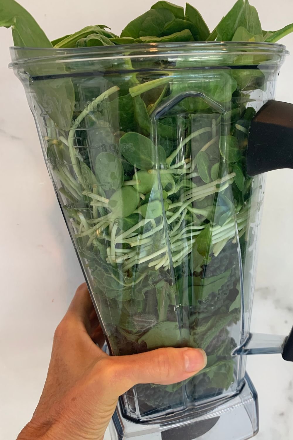 High-speed blender packed with fresh leafy greens for a green smoothie