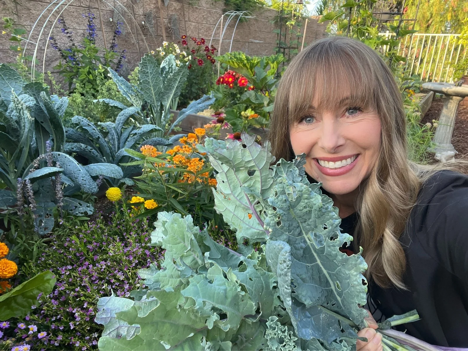 Michelle in her garden surrounded by leafy greens and vegetables