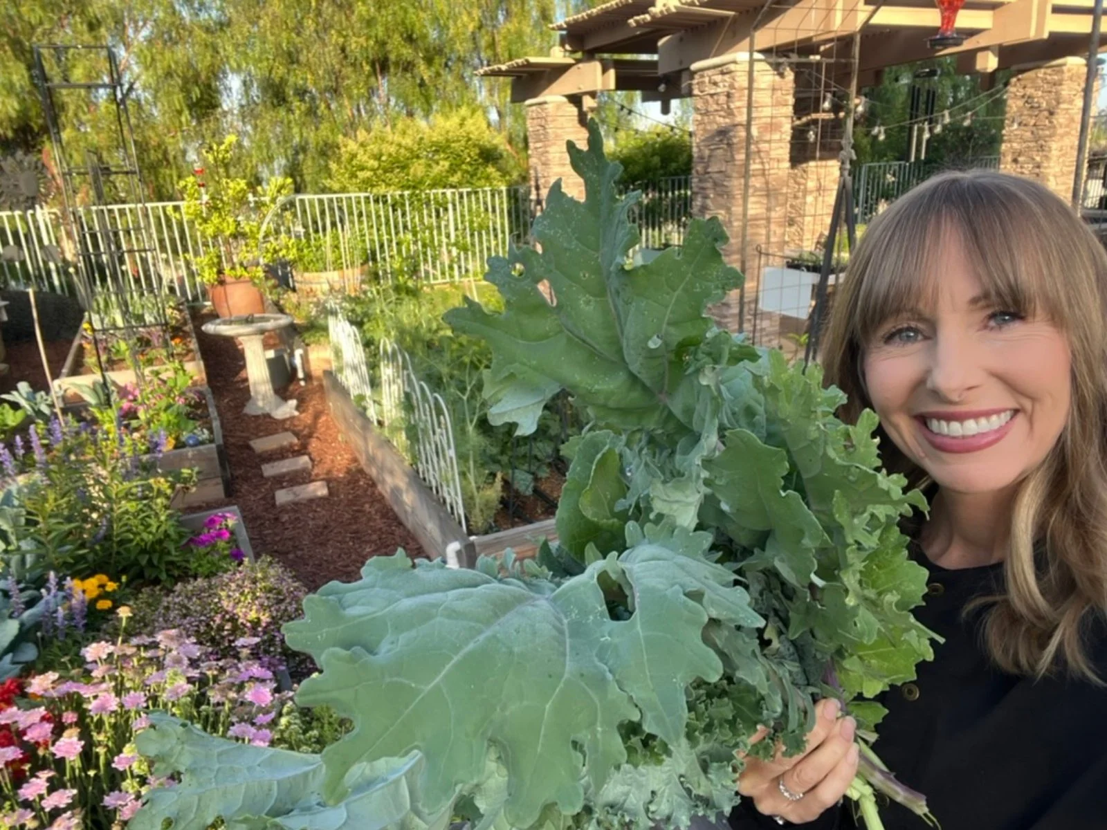 Michelle in her home garden holding freshly harvested greens