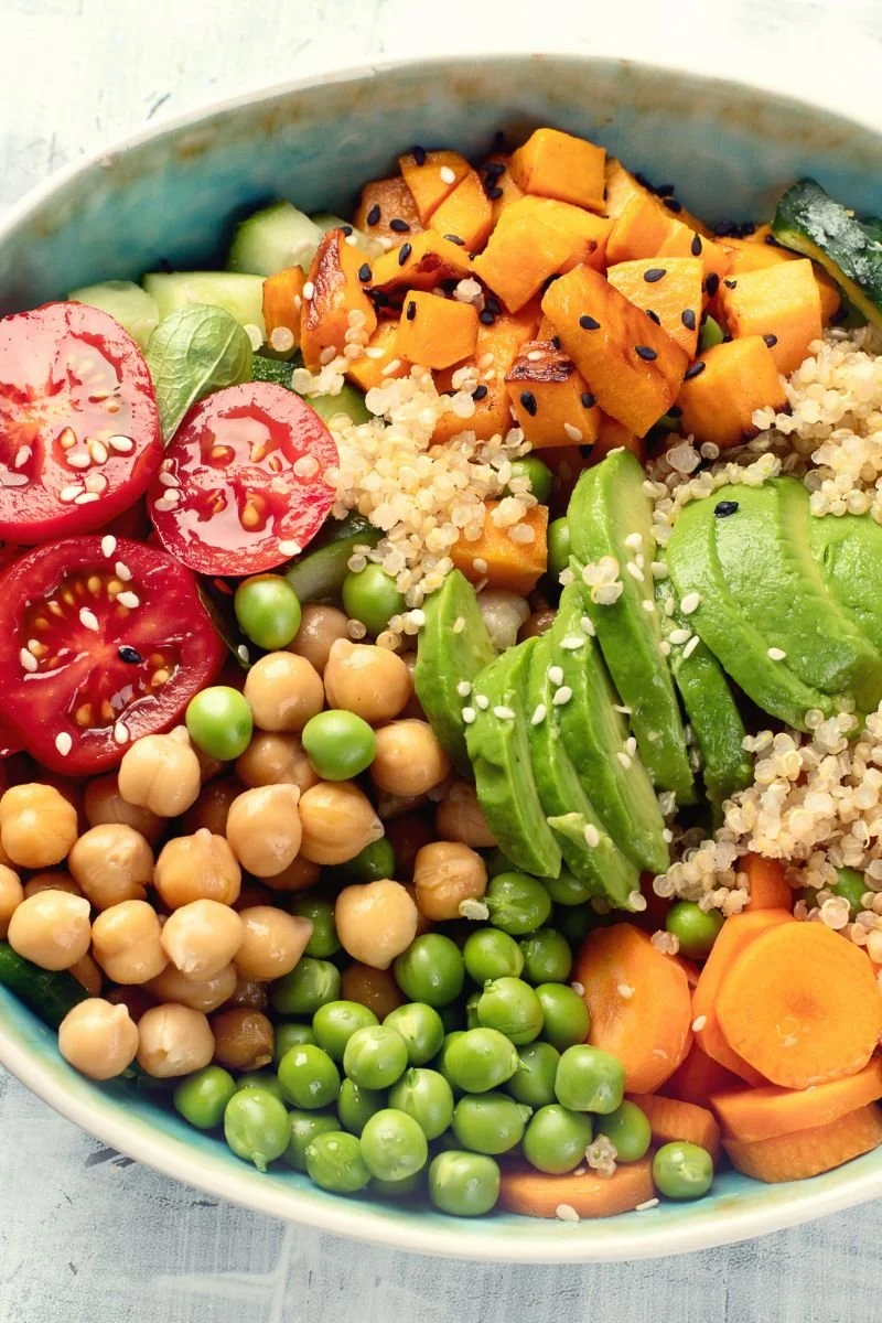 Plant-based bowl with chickpeas, avocado, quinoa, vegetables, and sweet potato.