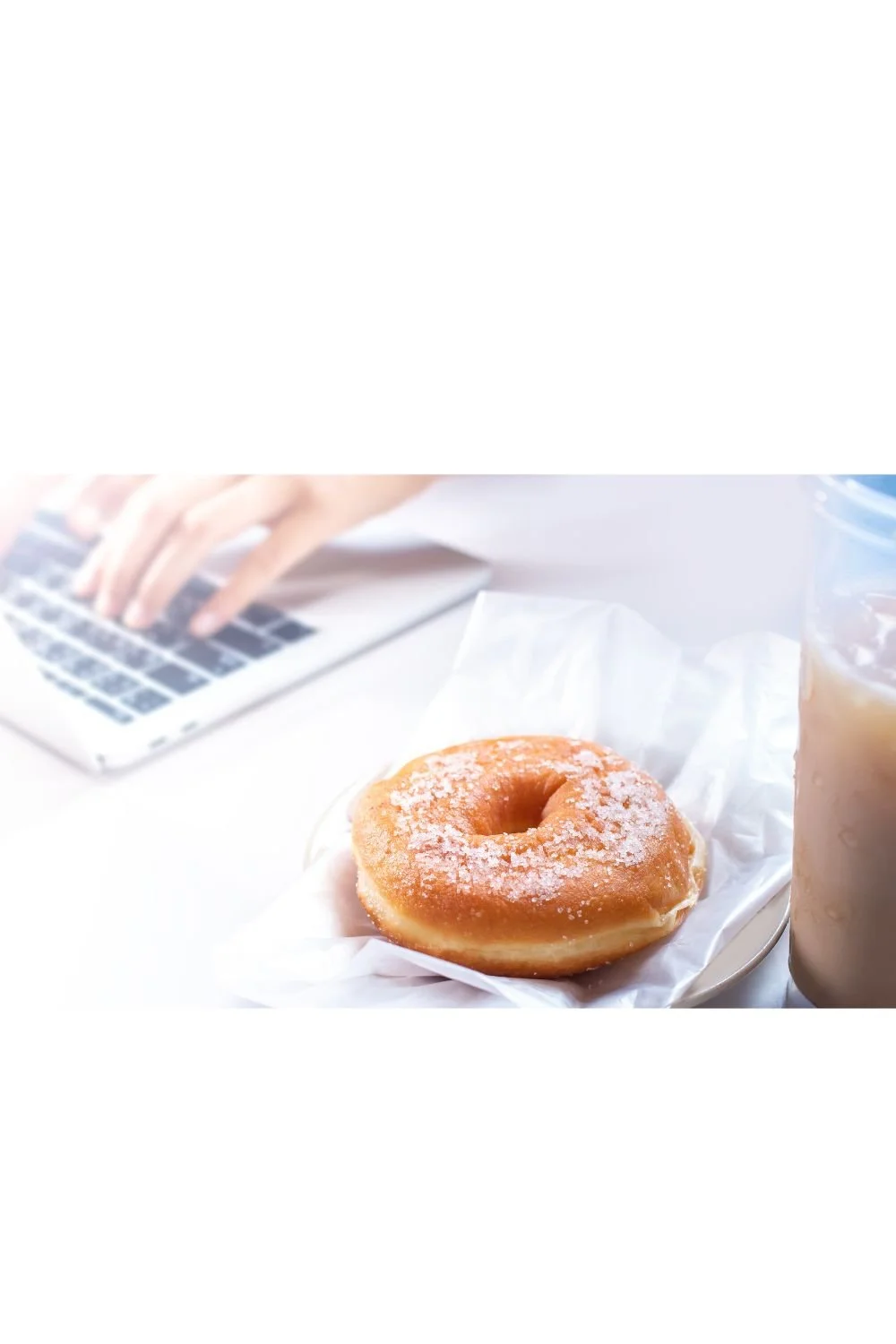 Doughnut beside laptop representing processed foods and modern lifestyle habits that can impact health