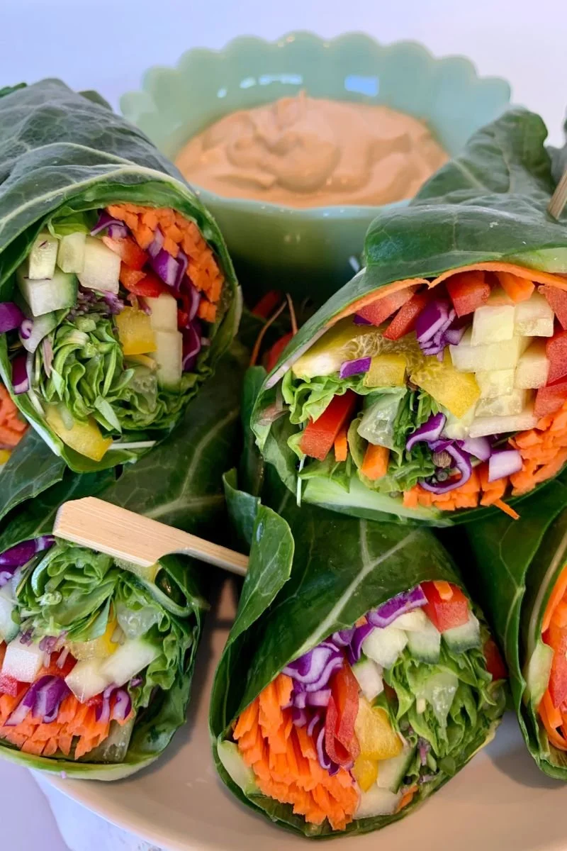 Raw vegan collard wraps filled with cucumber, peppers, carrots, cabbage, and leafy greens.