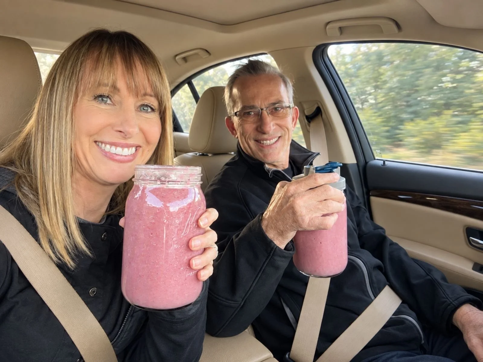 Couple holding smoothies in the car while following Dr. Brooke Goldner's Goodby Autoimmune Protocol in everyday life.