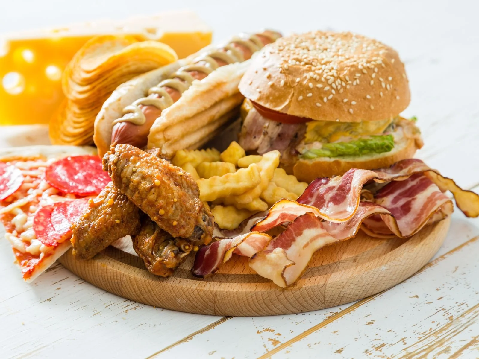 Assortment of ultra-processed foods including burgers, fries, pizza, bacon, and chicken wings
