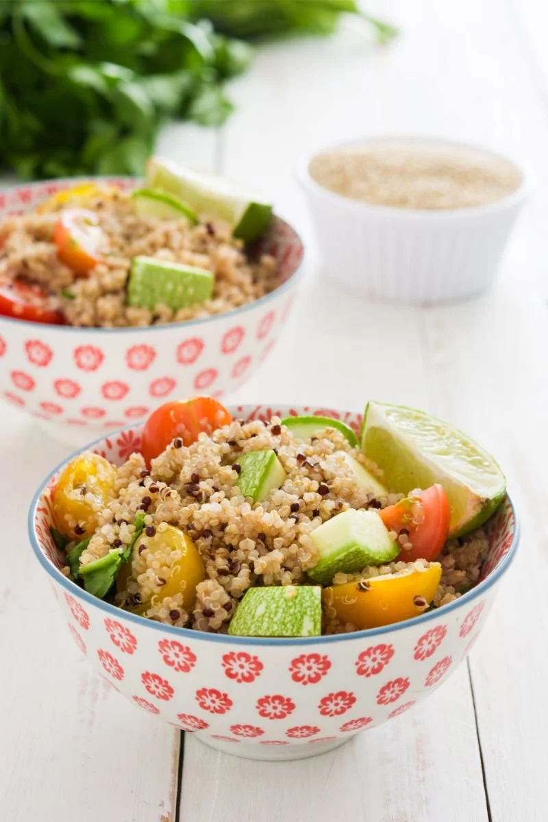 Plant-based quinoa bowl with avocado, cherry tomatoes, lime, and fresh vegetables