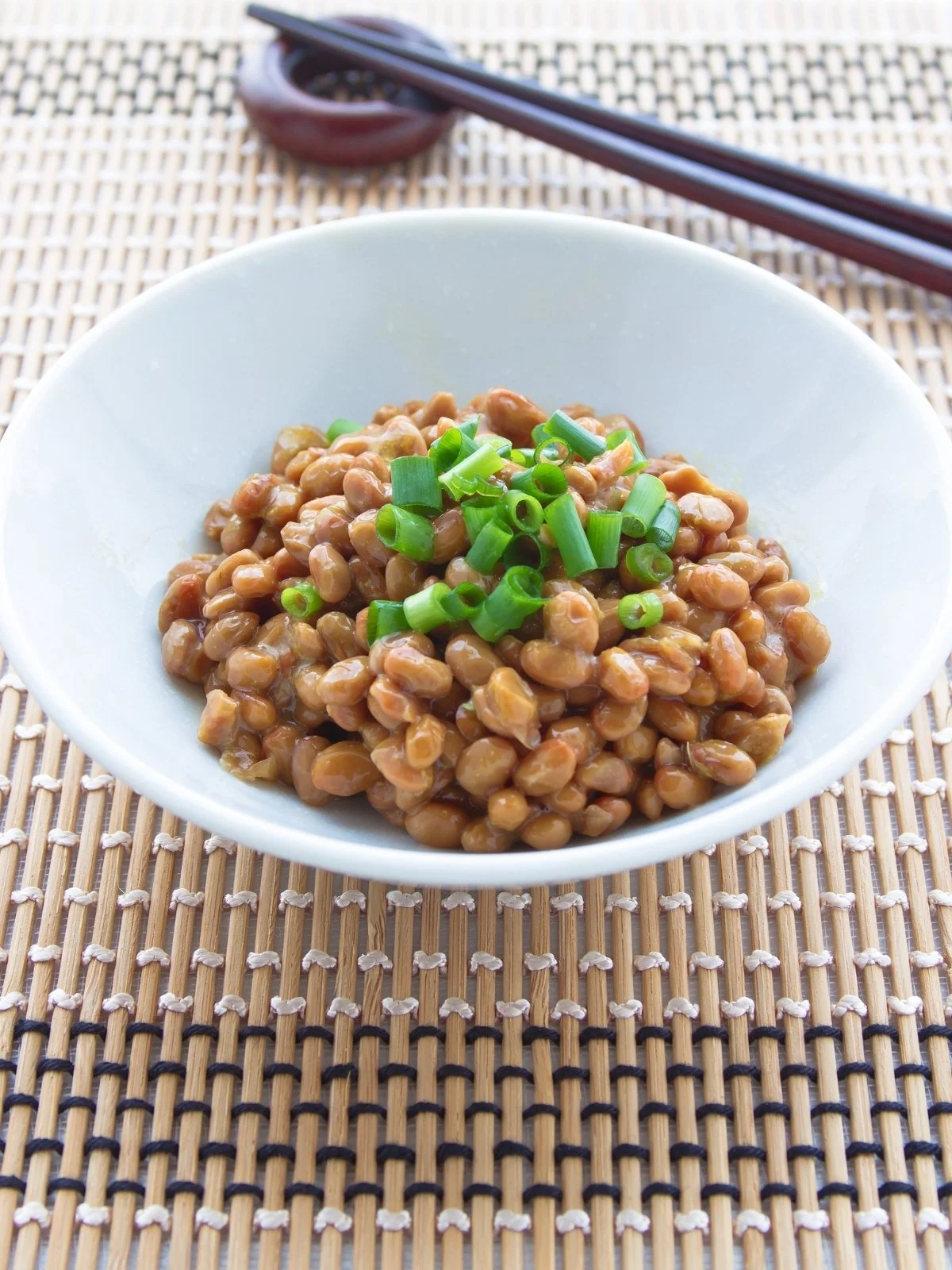 Bowl of natto fermented soybeans topped with chopped green onions.