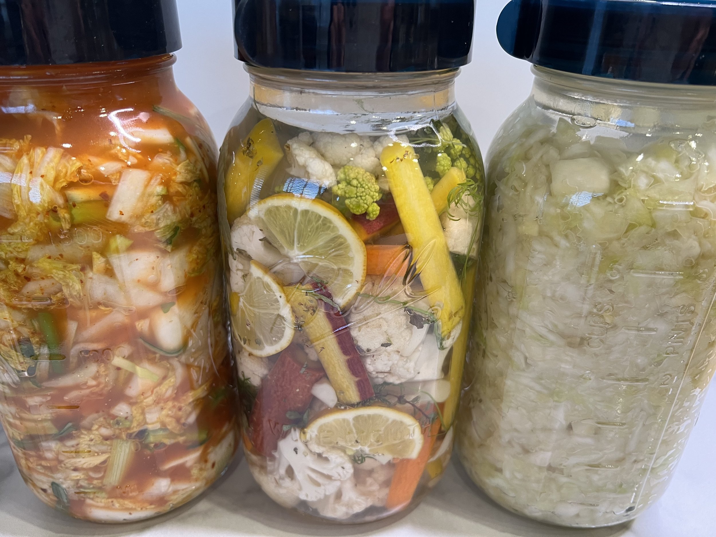 Colorful homemade fermented vegetables in glass mason jars.