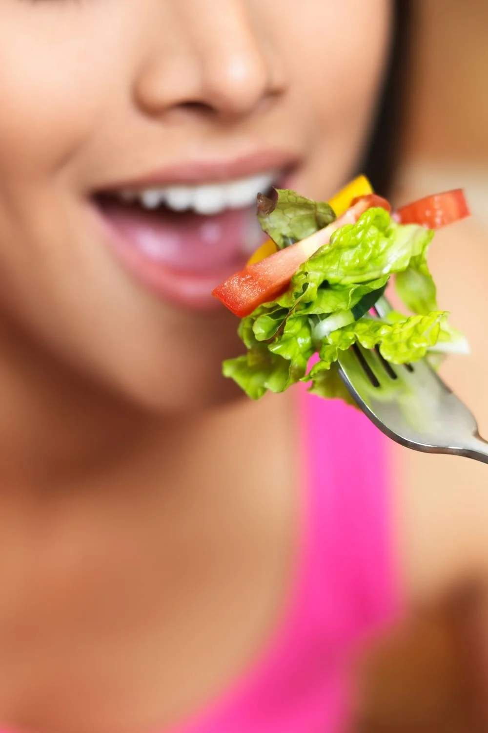 Person eating a fresh salad with lettuce and vegetables.