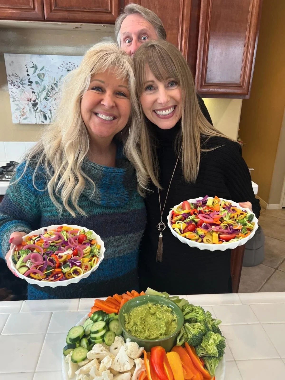 Two sisters holding colorful salads at a family gathering while following Dr. Brooke Goldner's Goodbye Autoimmune Protocol.