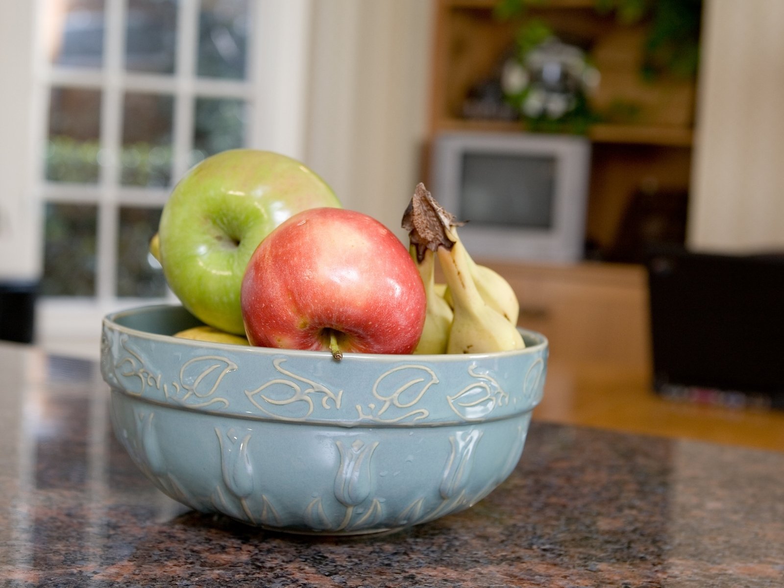 Bowl of fresh apples and bananas on a kitchen counter.