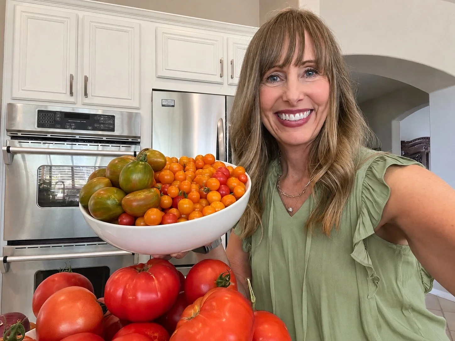Michelle holding a bowl overflowing with colorful homegrown tomatoes used to make fermented salsa.