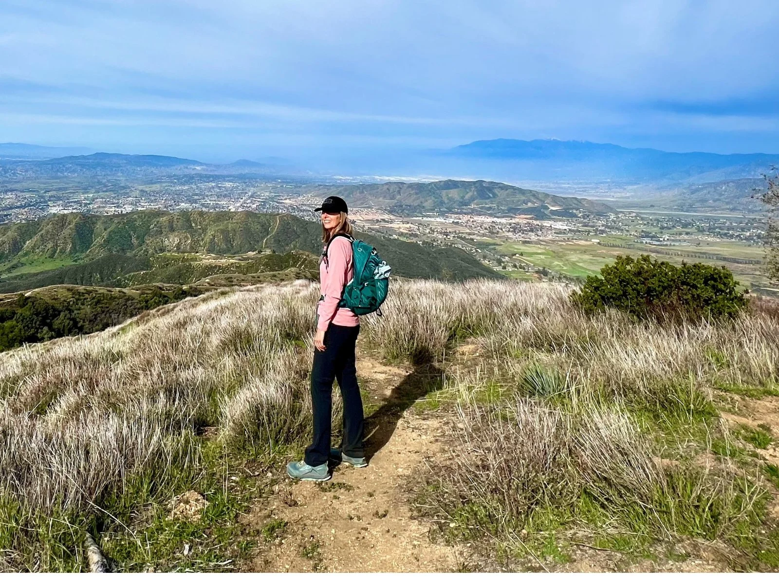 Woman hiking on a hillside overlooking the mountains and valley