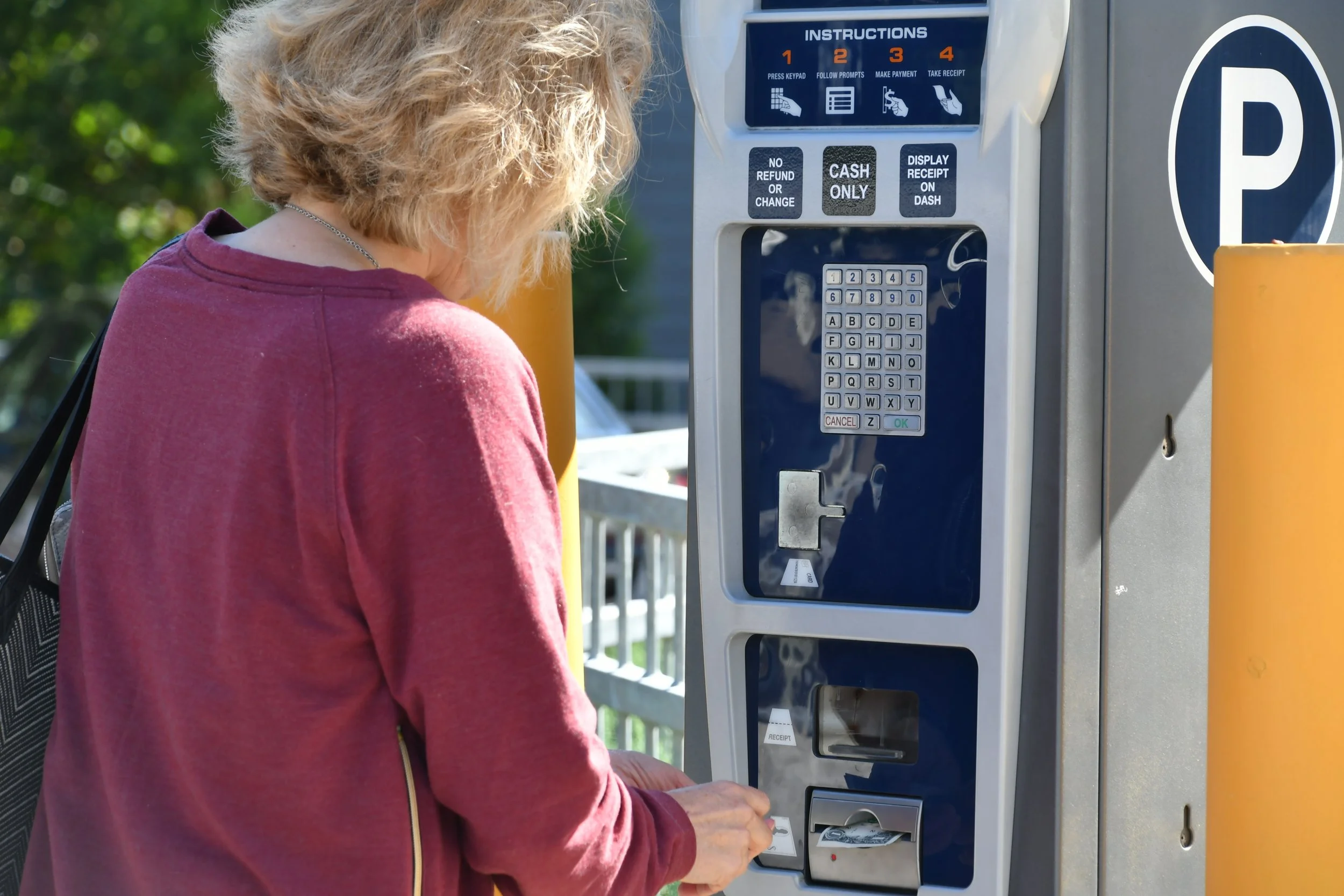 a-woman-putting-money-dollar-bills-into-a-parking-2022-11-14-04-07-28-utc.jpg