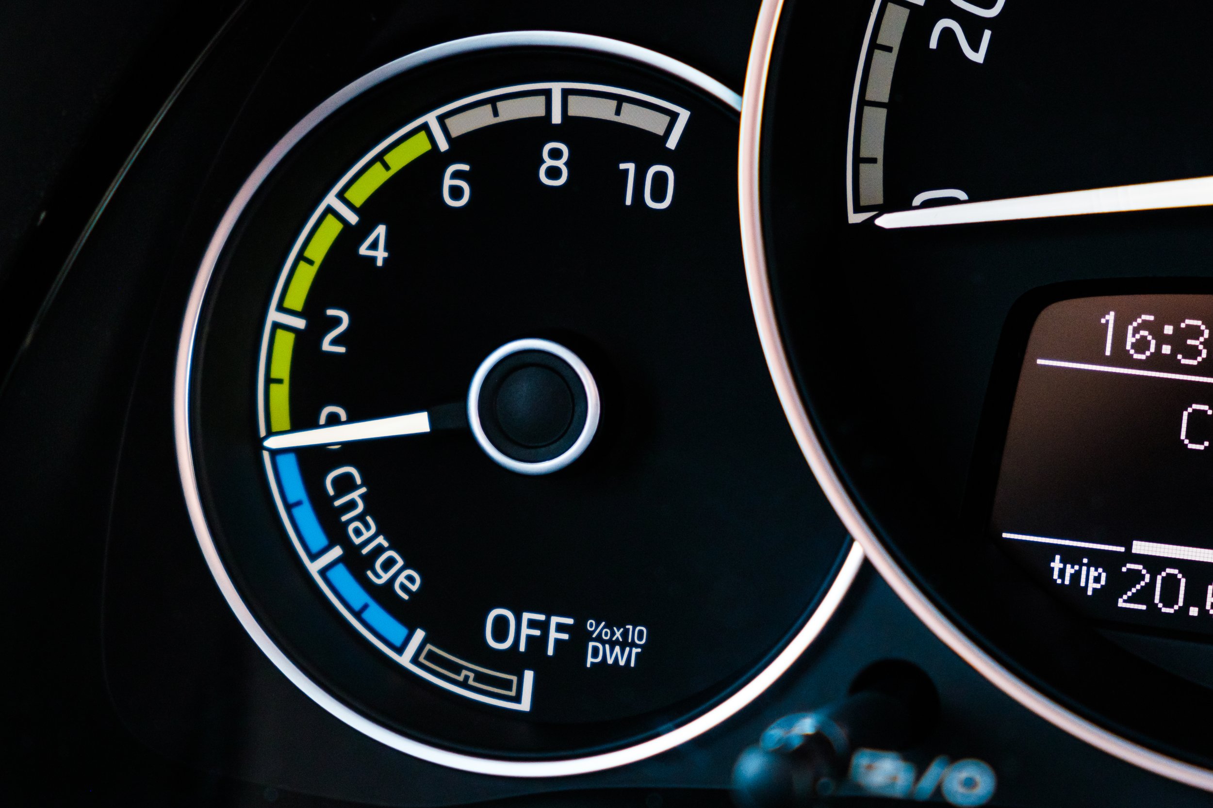 Car dashboard showing the fuel gauge close to empty, with the needle near the low fuel indicator, and an digital display showing the time 16:3 and a trip distance of 20.8 miles.