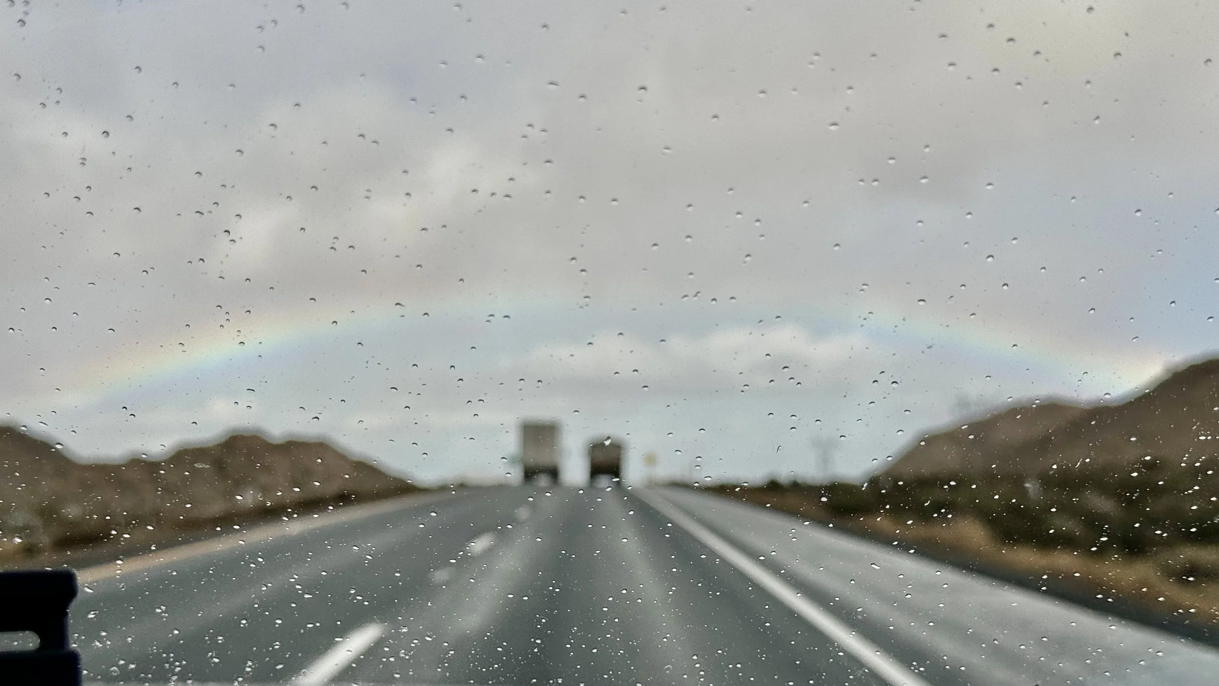 "Even through the rain and obscured road, always trusting in the Lord to lead us.", A random highway in the rain with the hint of a rainbow, photo and description by: Traci Schuck