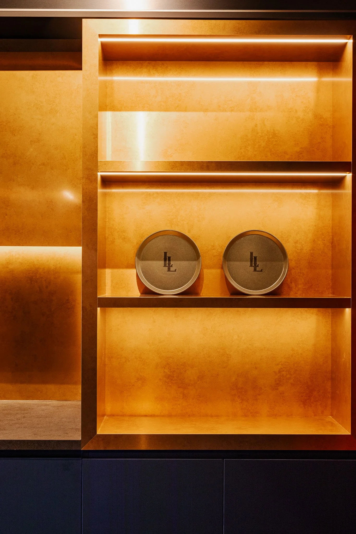 Brushed brass custom joinery and monogrammed plates at a private suite at a sports stadium in Sydney