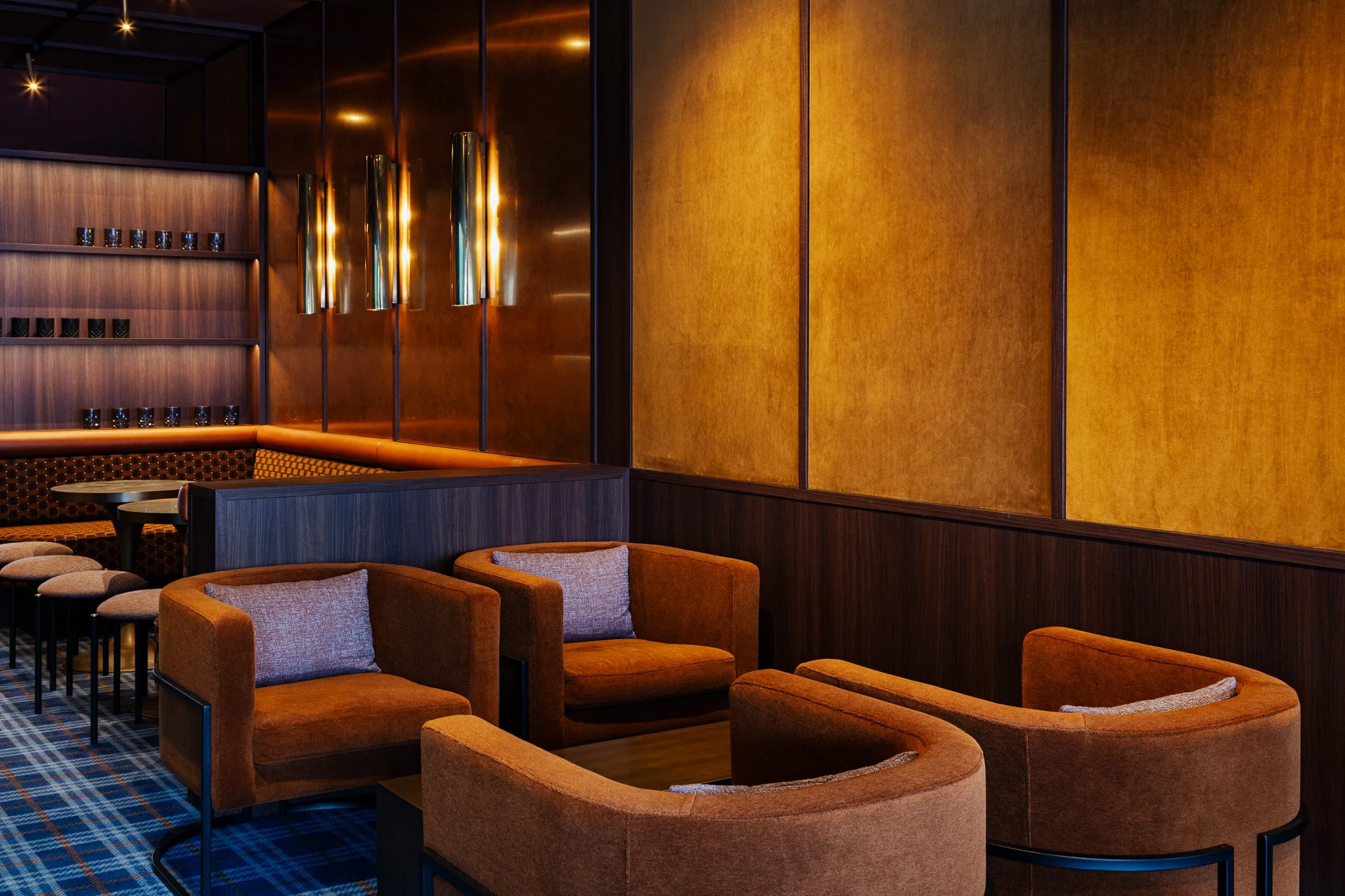 Brushed brass wall with leather arm chairs in a lounge at a sports stadium