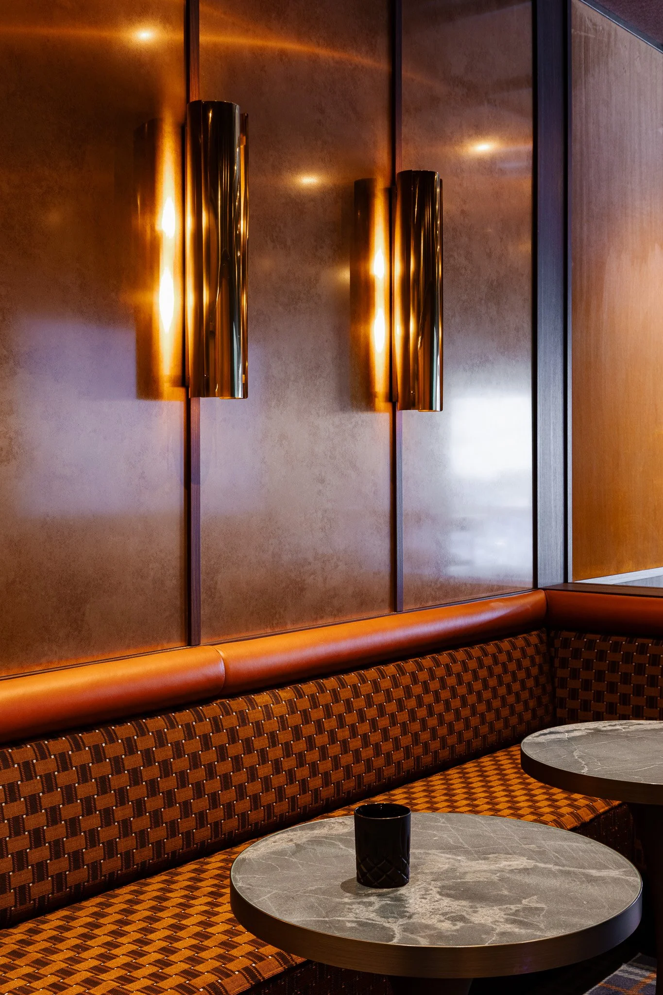 Metallic cylindrical light fittings and marble dining tables in a sports stadium suite