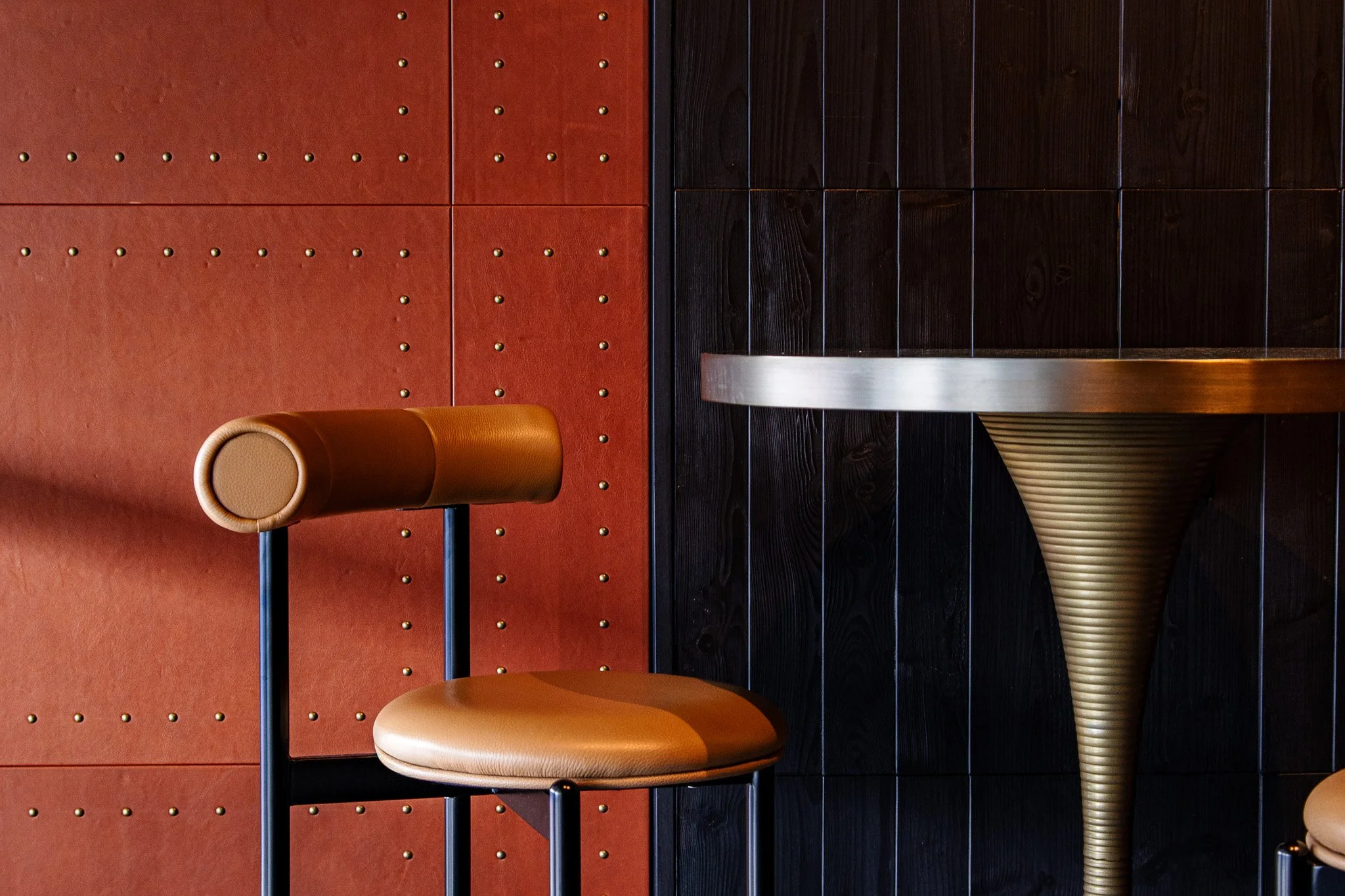 Leather bar seat and table against a leather-clad wall.