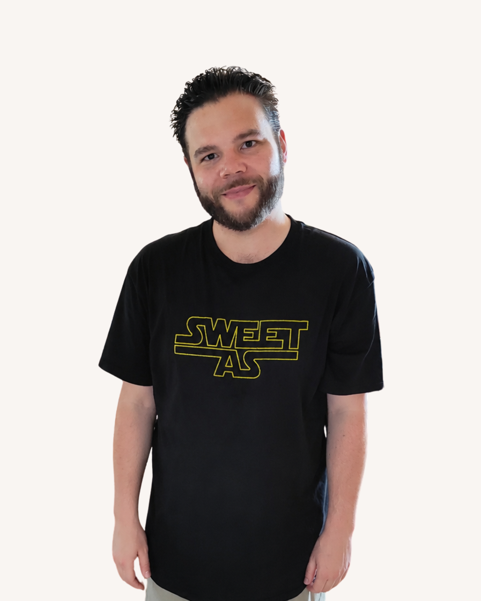A young man with dark hair, beard, and light skin, wearing a black T-shirt with yellow text that reads 'SWEET' and 'STAR', standing against a plain white background.