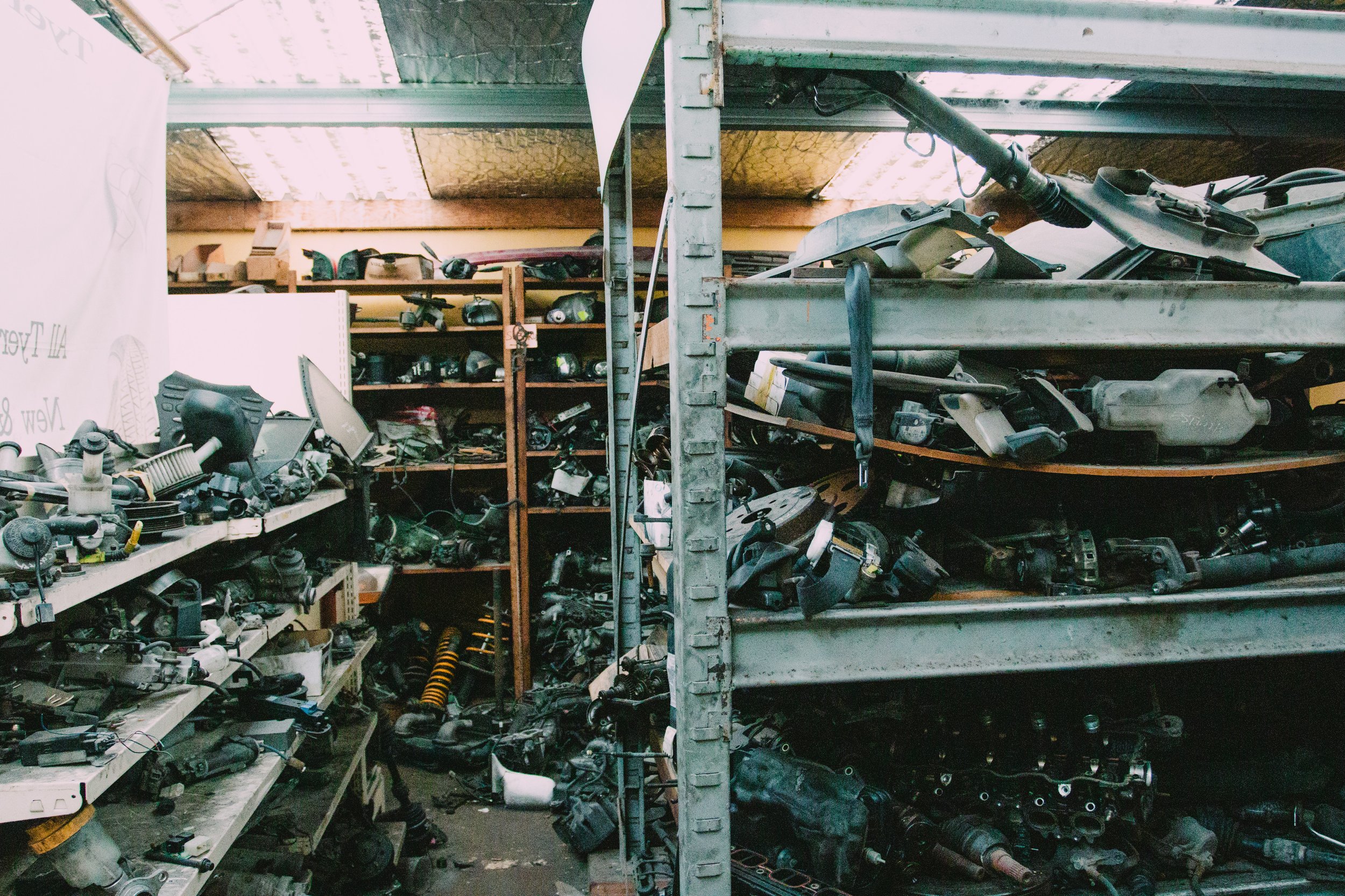 Interior of a cluttered auto parts store with shelves filled with various car components.