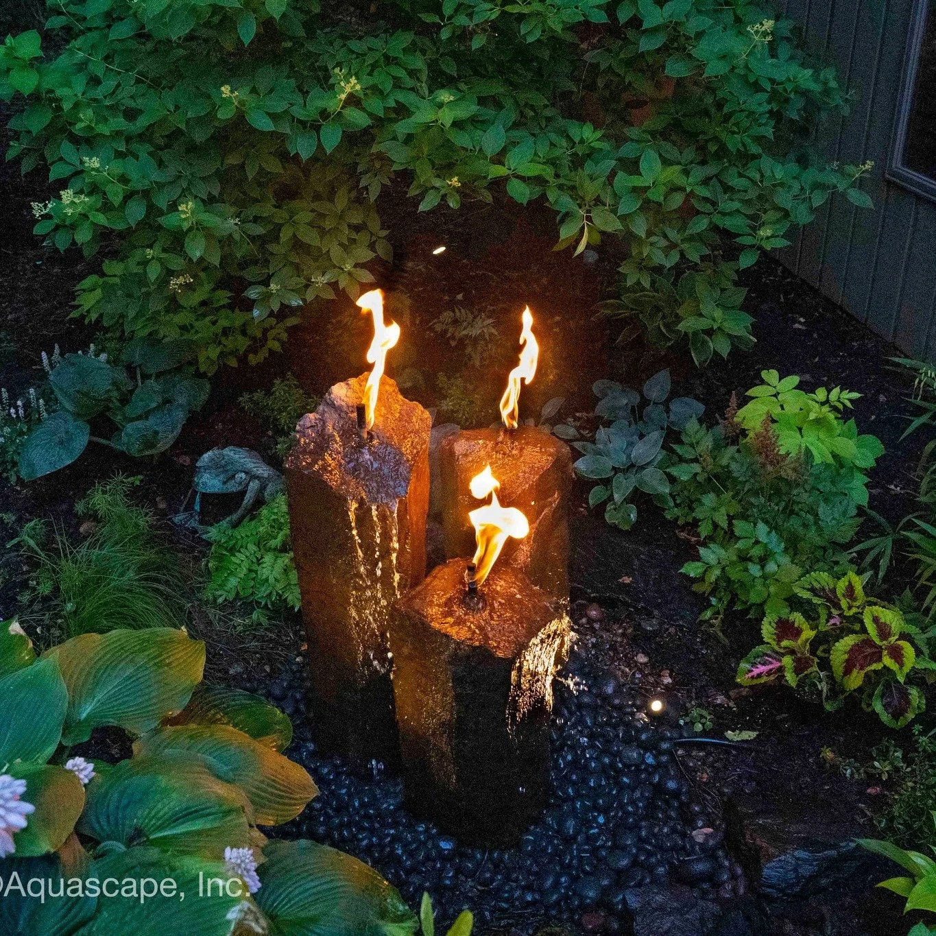 Evenings feel better when the yard has something worth looking at.

A lighted water feature brings movement, sound, and soft glowing reflections into the space after the sun goes down.

The water catches the light.
The stone adds texture.
The plants 