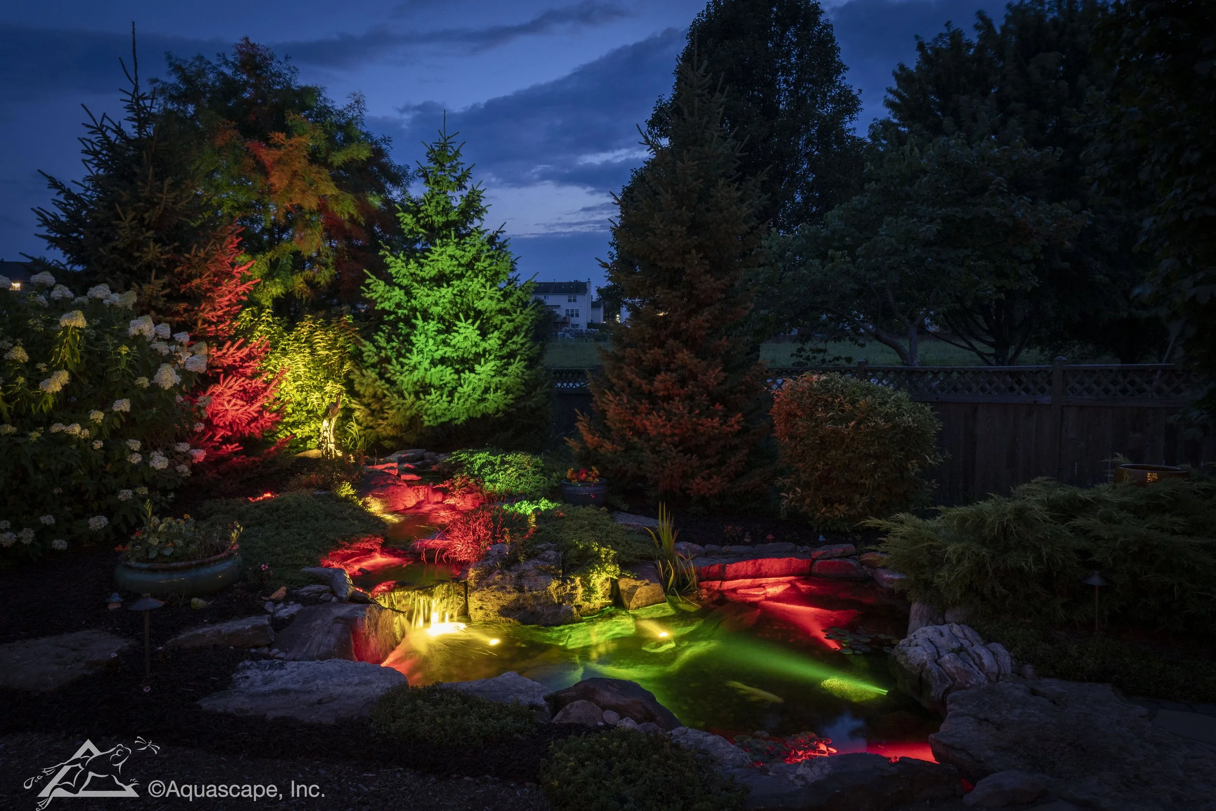 Nighttime garden scene with colorful illuminated waterfall and trees