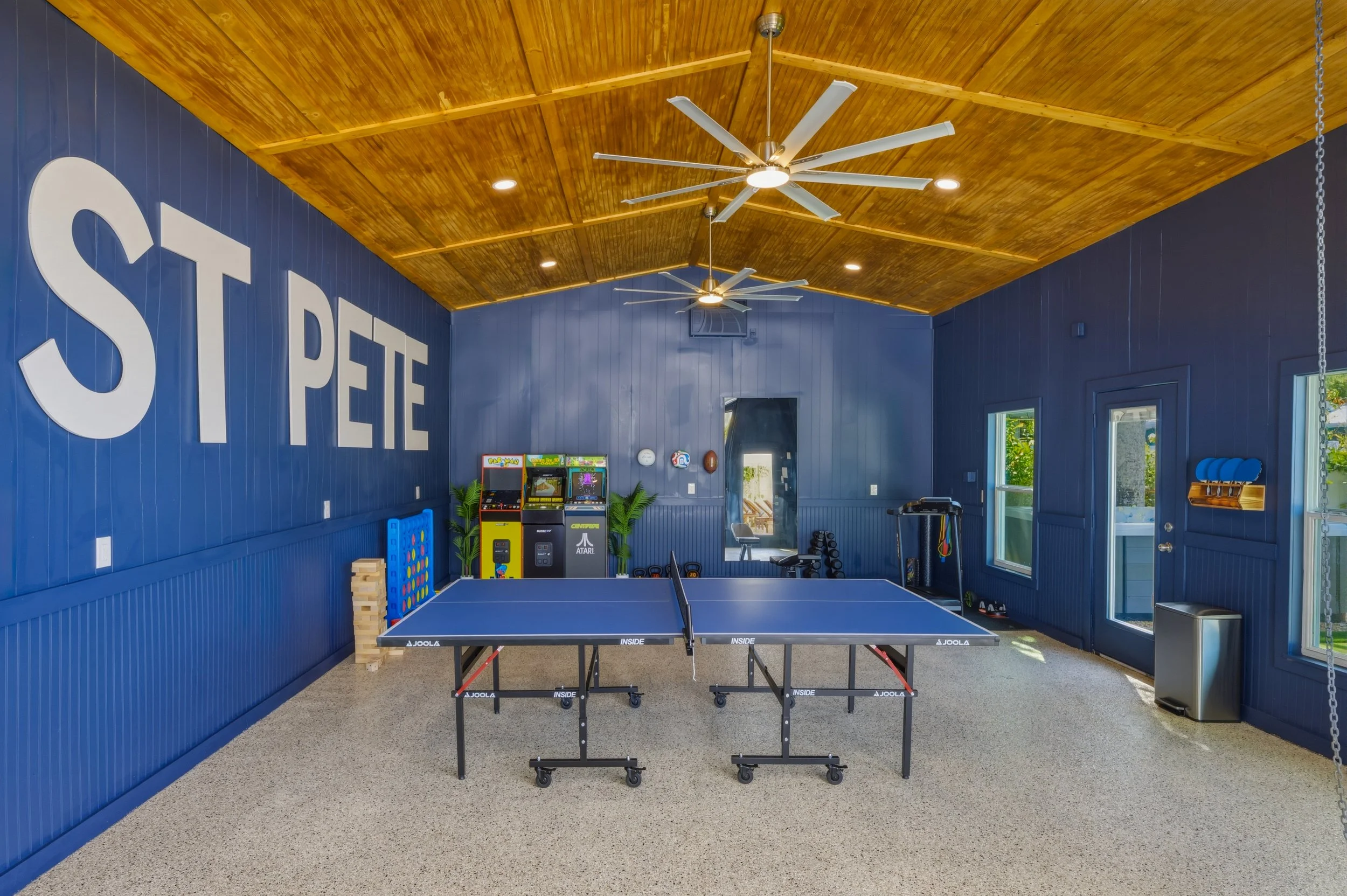 Indoor recreational room with blue walls, wood ceiling, ceiling fans, and ping pong table.