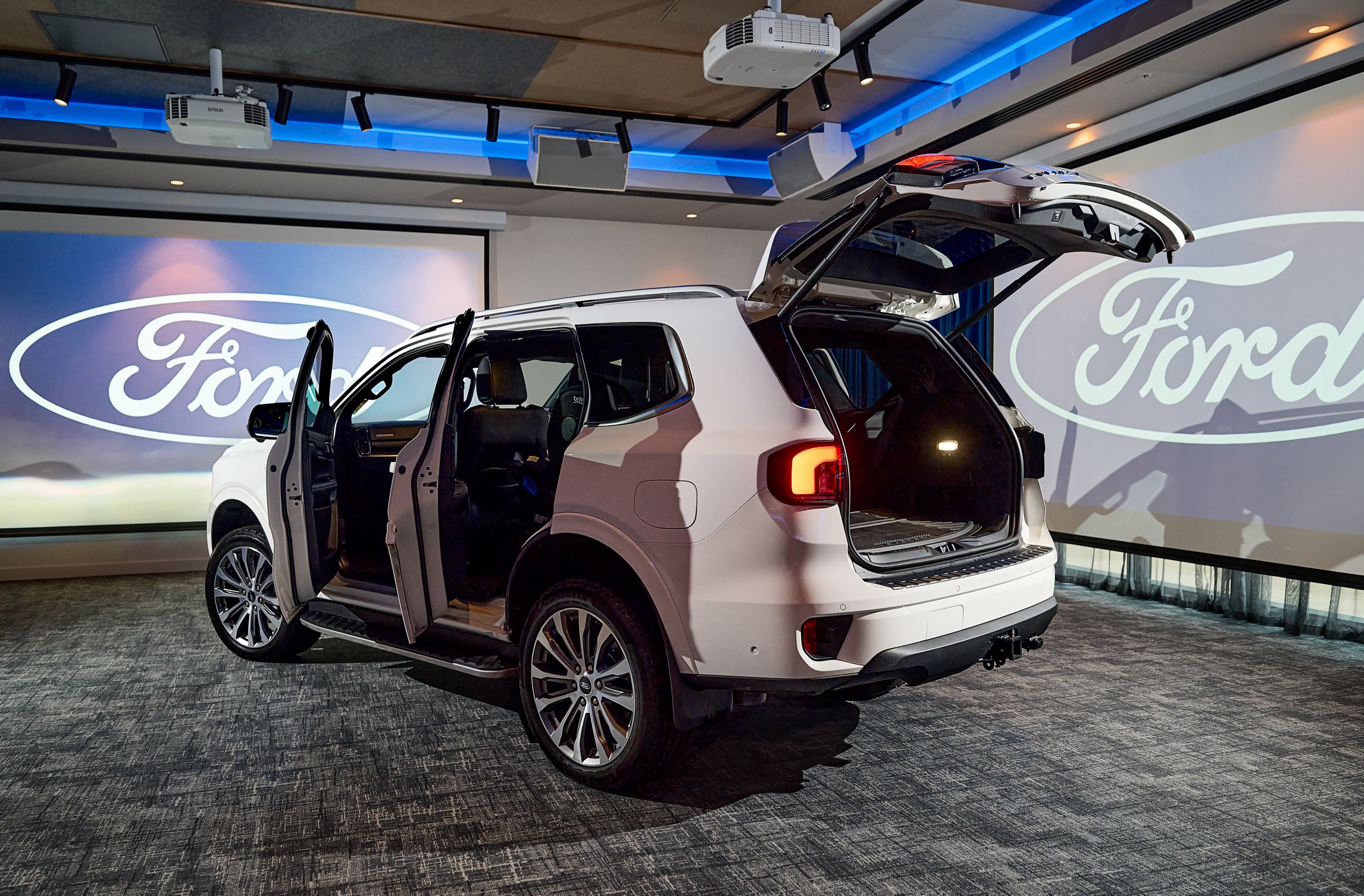White SUV with doors open in a Ford showroom