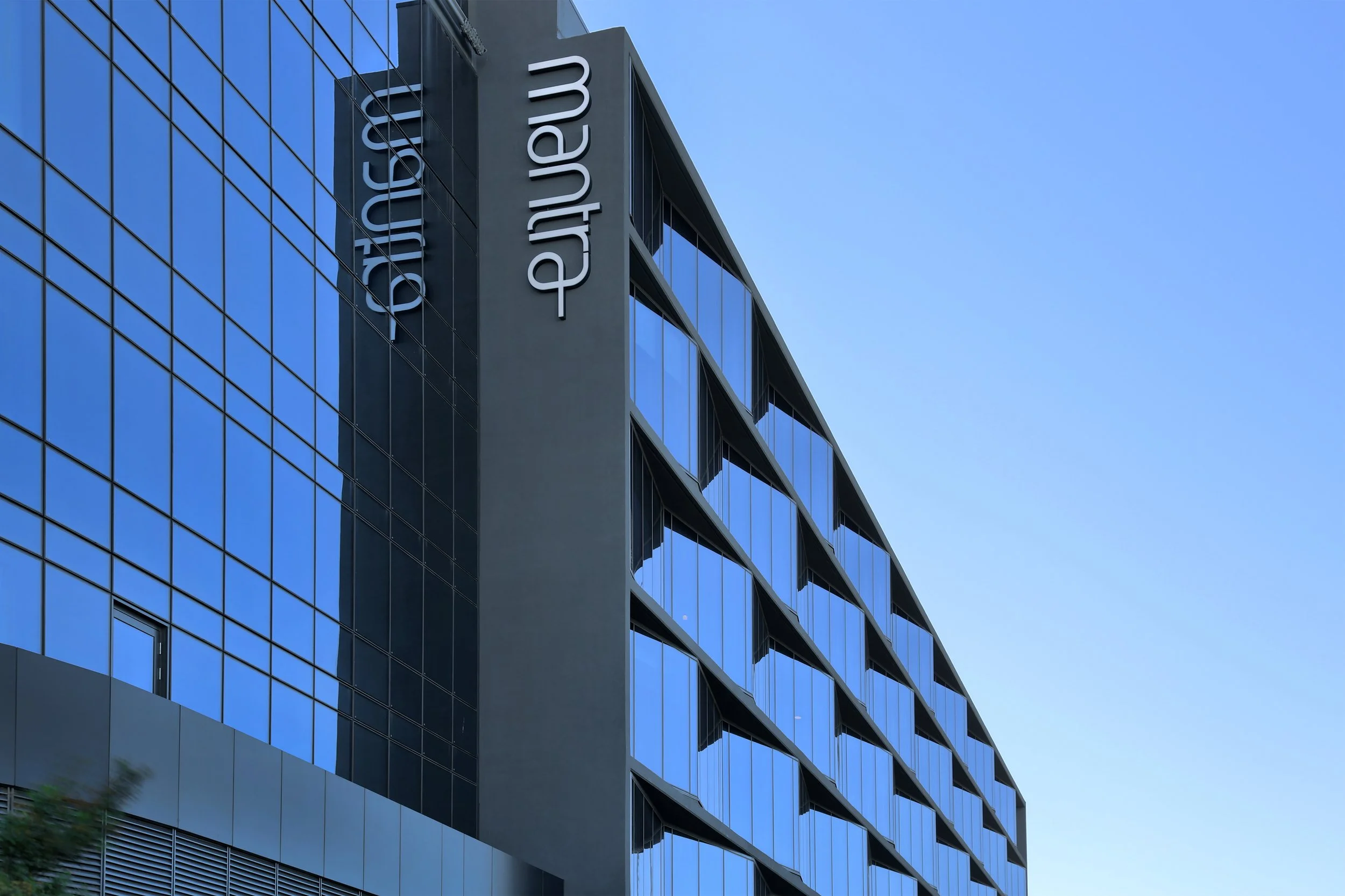 Modern hotel building with reflective glass windows and 'mantra' signage.