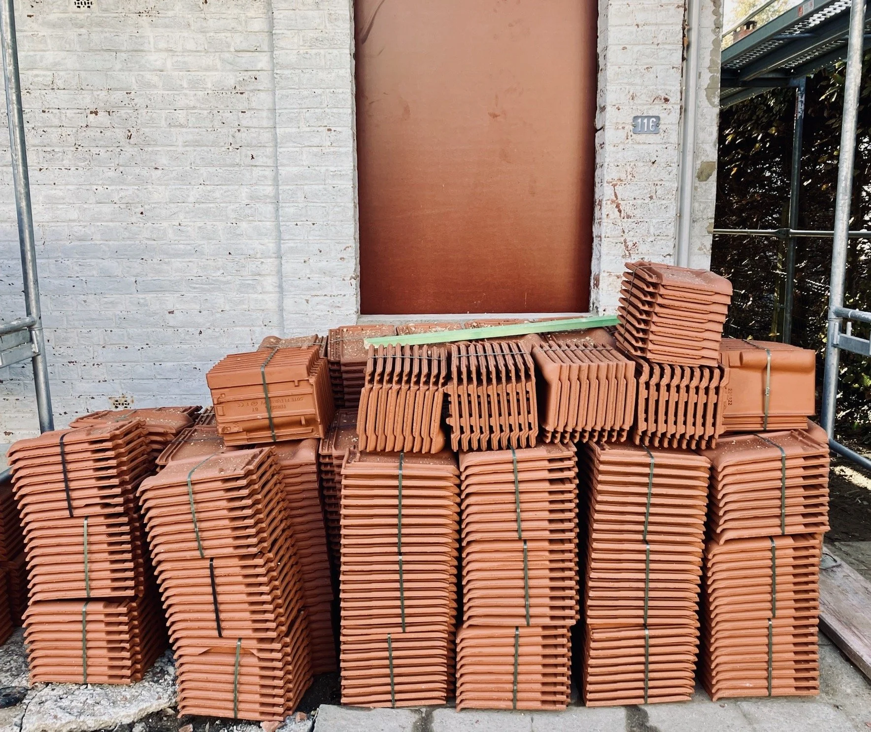 Empilements de tuiles en terre cuite devant une porte en brique