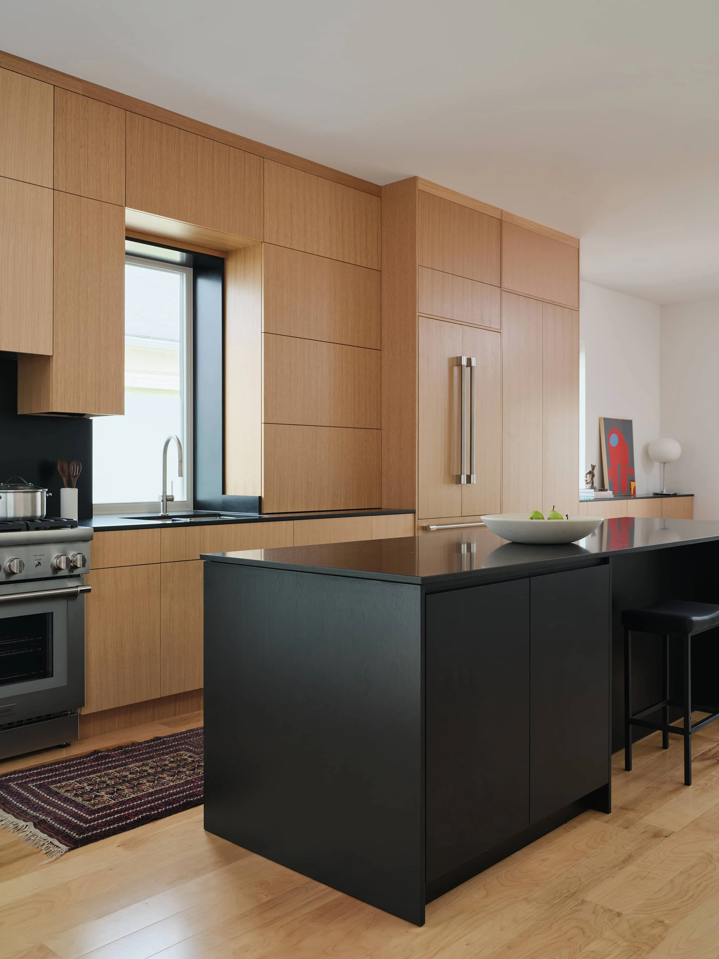Modern kitchen with tall wooden minimalist cabinets, a sleek black wood island and modern decorative accents