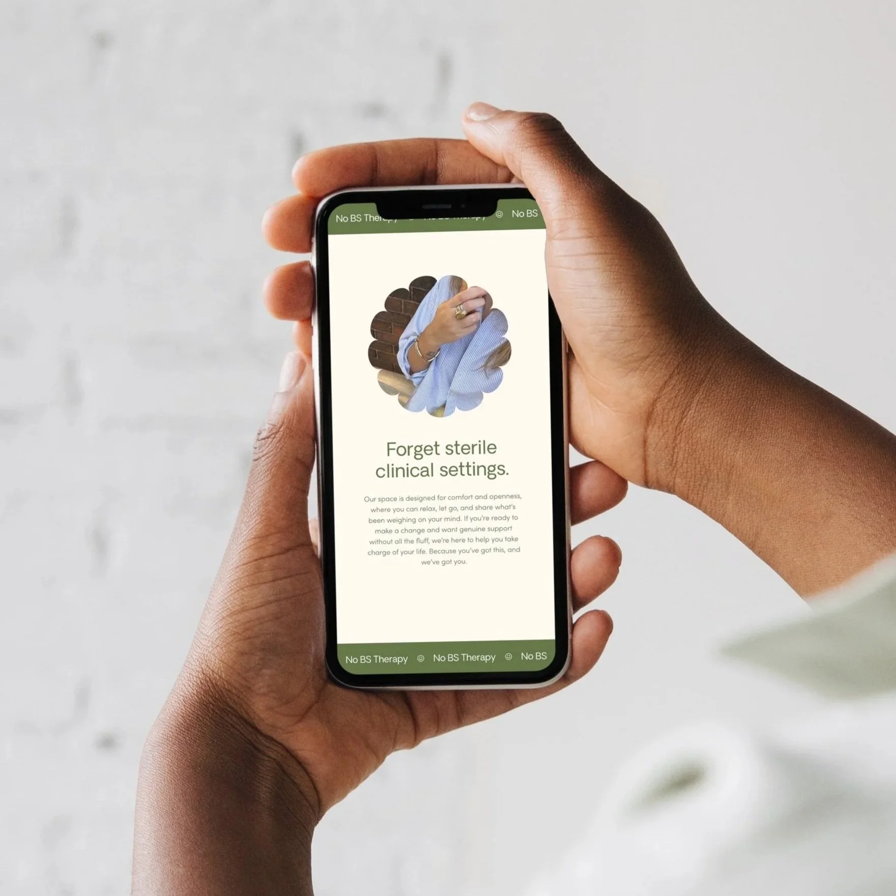 A person holding a smartphone displaying a website, with an image of a hand holding a cloth and text that says 'Forget sterile clinical settings.'