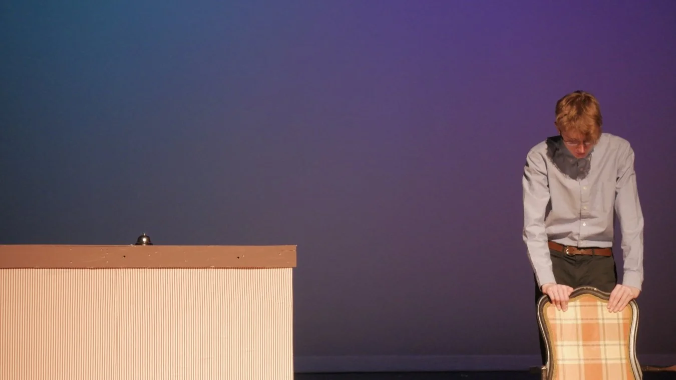 Mason Lester standing over a chair in Jax Schuck's Entropy.