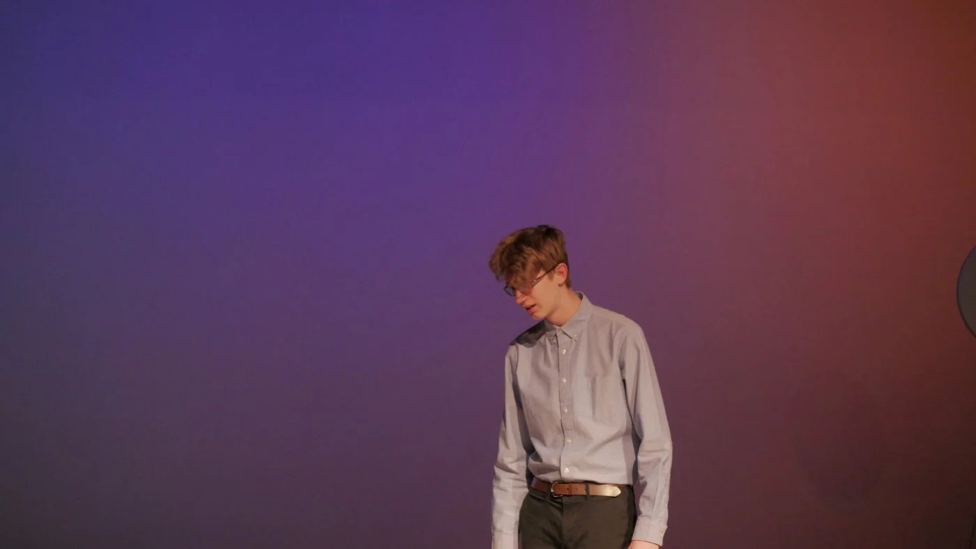 Mason Lester standing in front of a colorful backdrop in Jax Schuck's Entropy.
