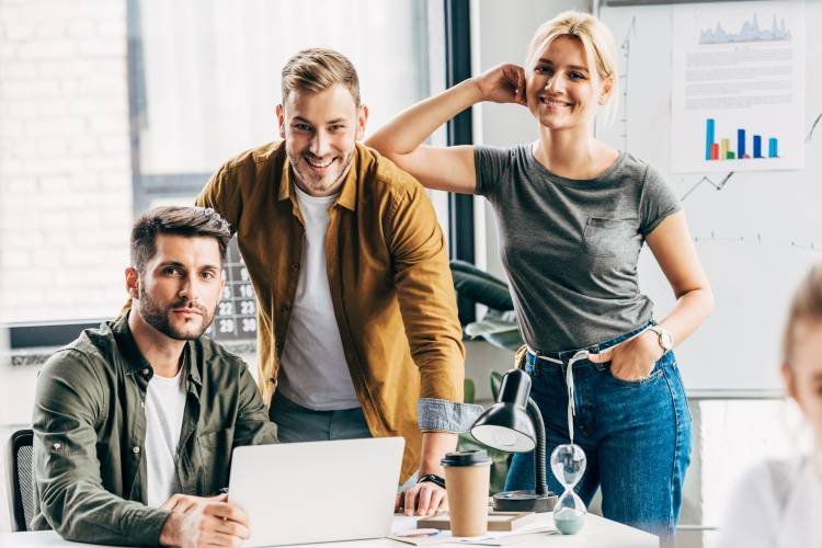 jong team van drie personen kijkt lachend in de camera