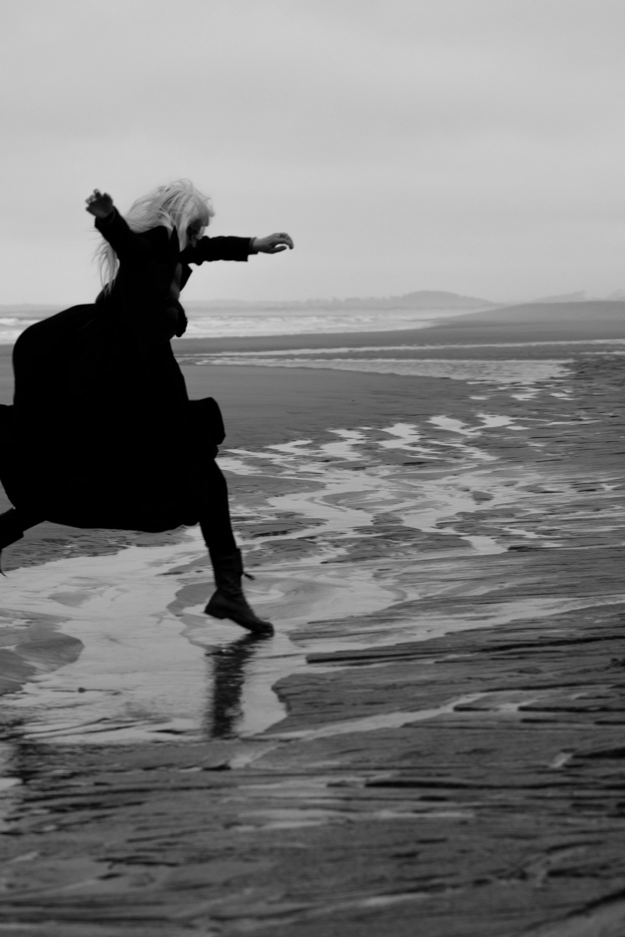 Libby DeLana jumping a tide pool at the beach