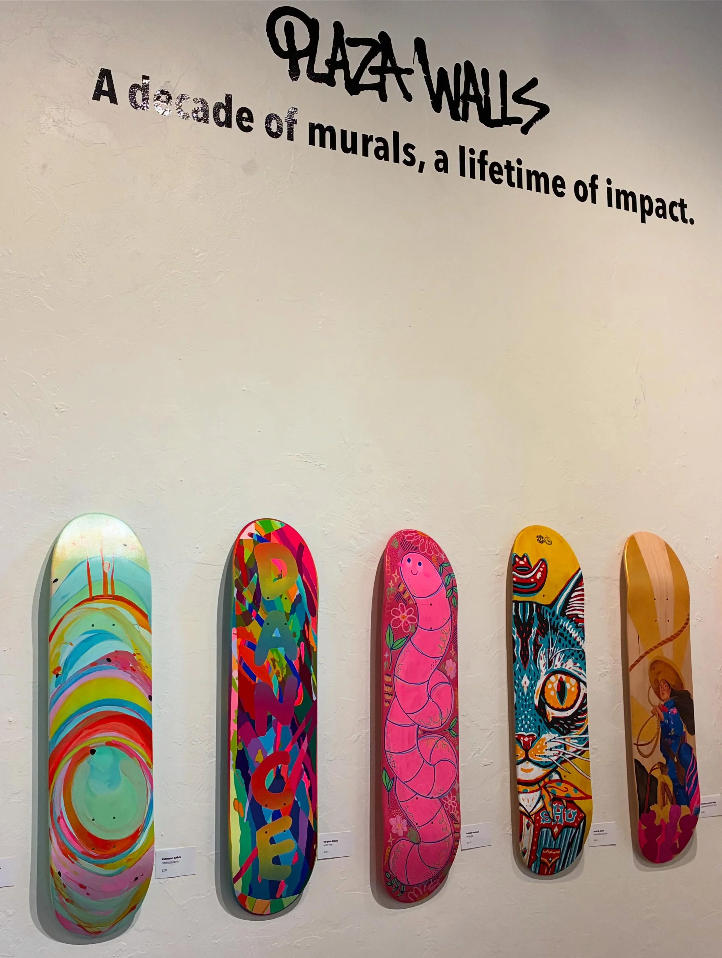 Wicked Awesome Skate Deck Show 2 currently up at @plazawalls gallery! curated by @circlogic and @virginiasitzes 
All sales support the annual Plaza Walls Mural Expo 🔥

I&rsquo;m loving the blend of artists on this wall 😍😍😍 with boards by (left to