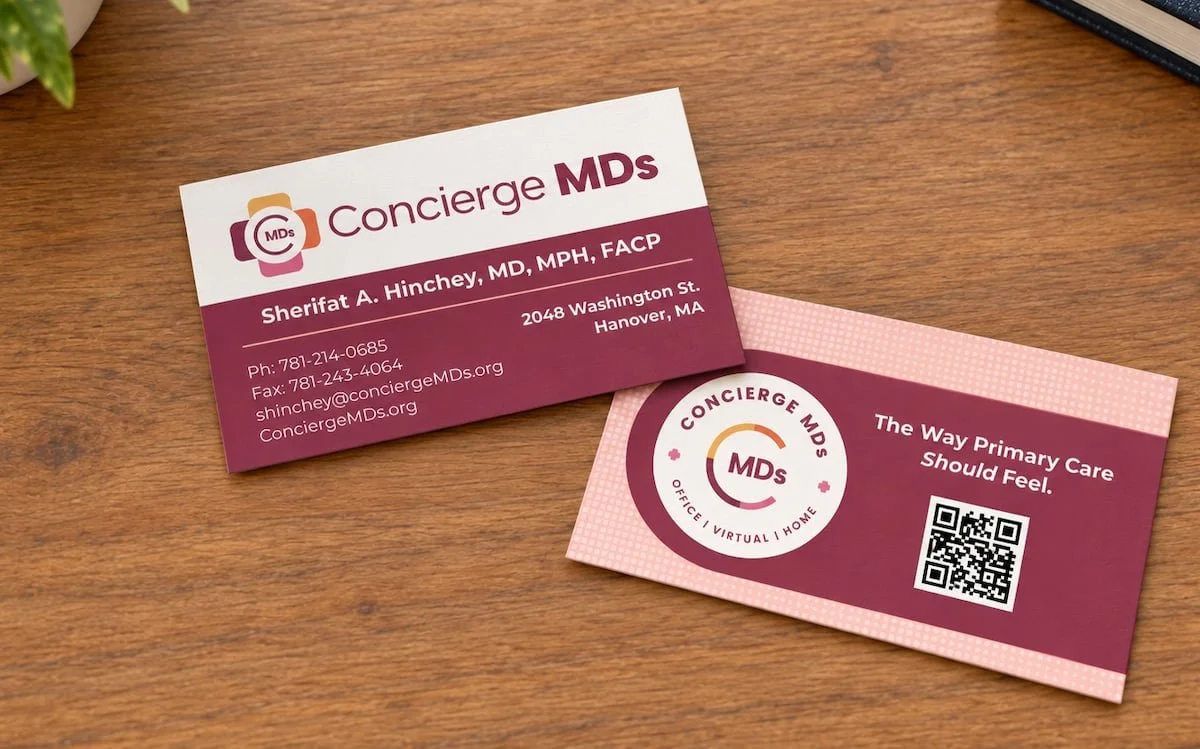 Business card and marketing card for Concierge MDs on a wooden desk.