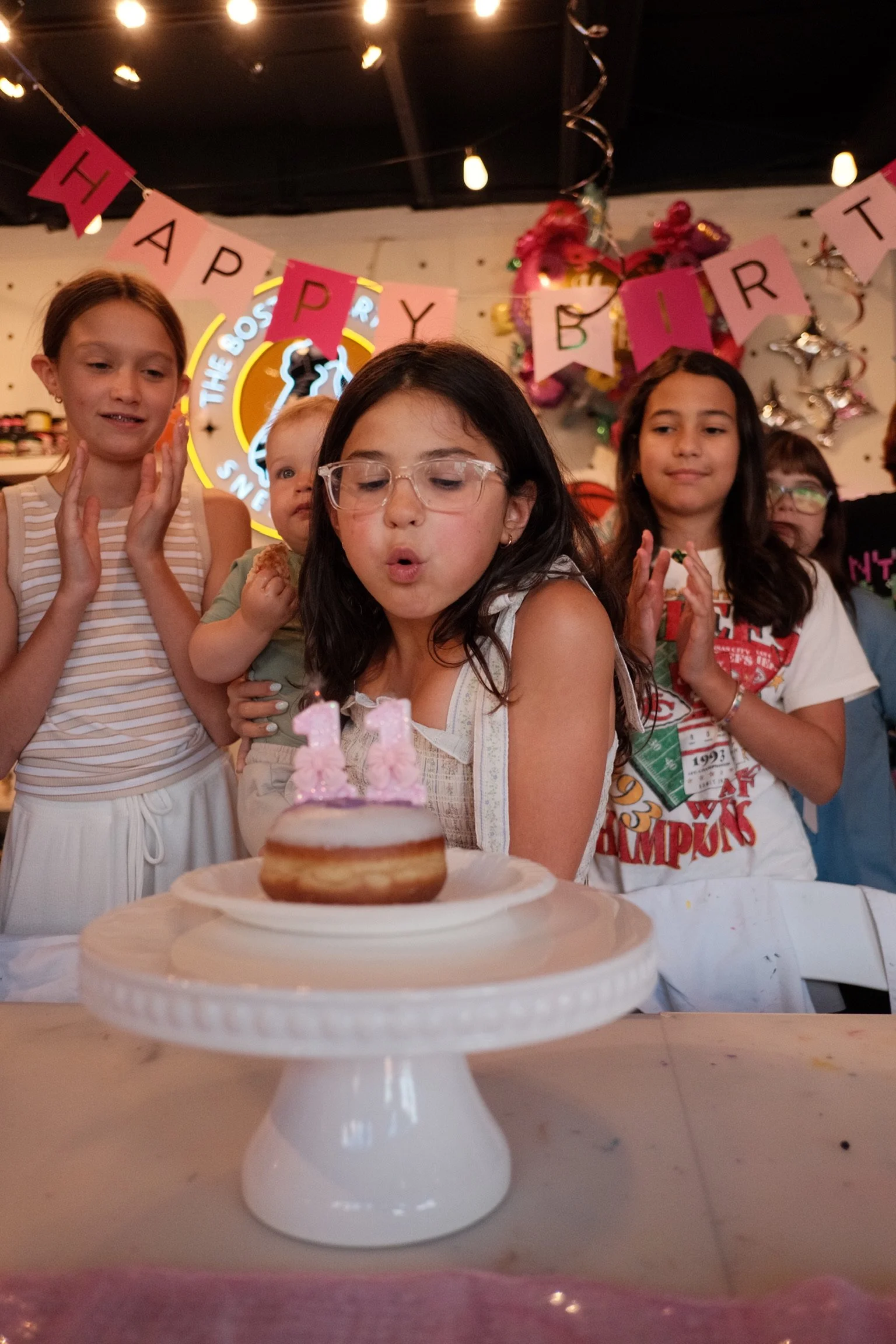 Children celebrating a birthday and blowing out candles during a creative party at The Boston Artistry in Hingham, Massachusetts.