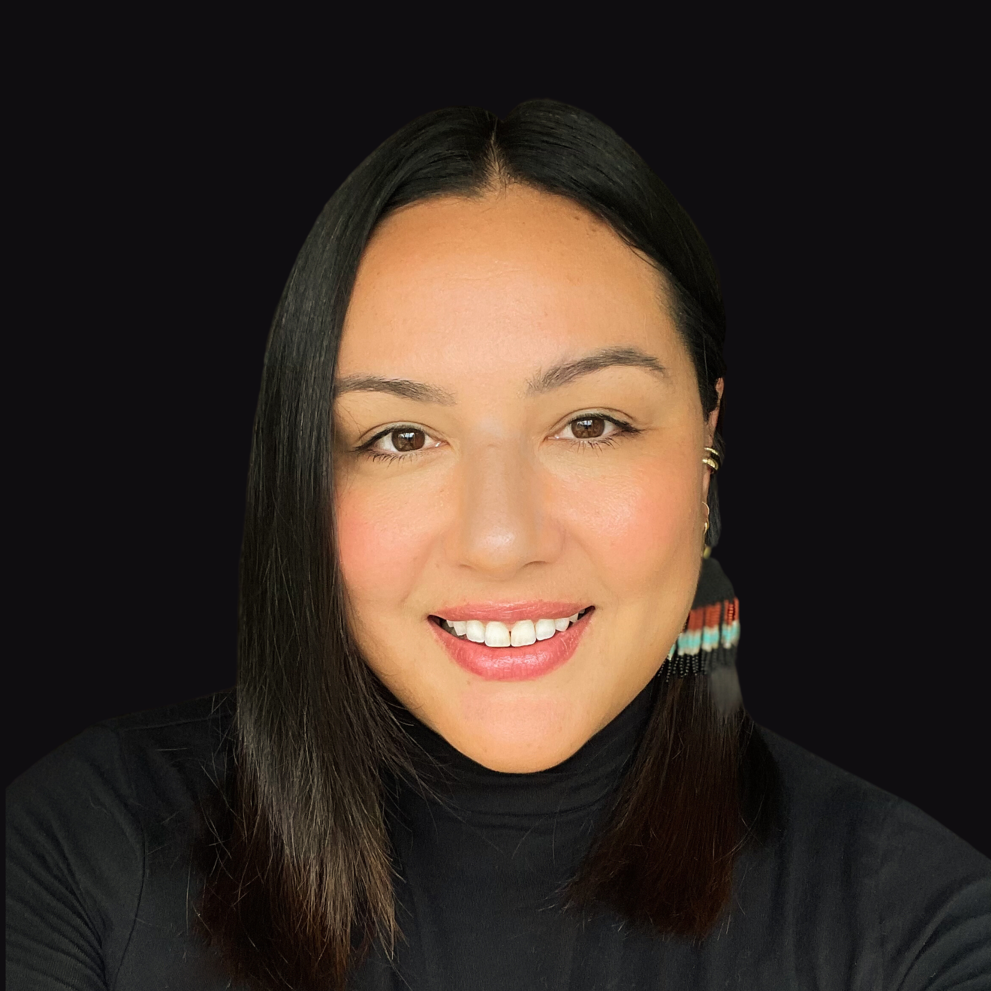 Smiling person with long dark hair wearing a black top, featuring colorful earrings against a black background.