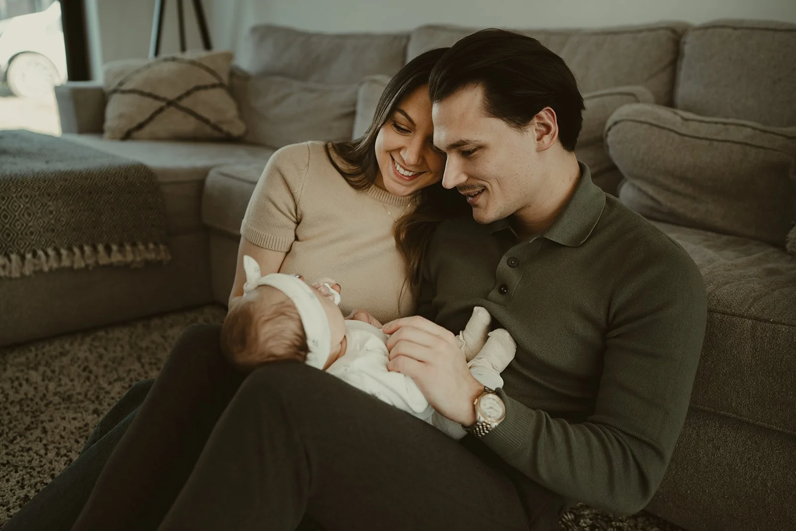 Un couple jeune avec un bébé regarde et sourit à leur bébé dans un salon