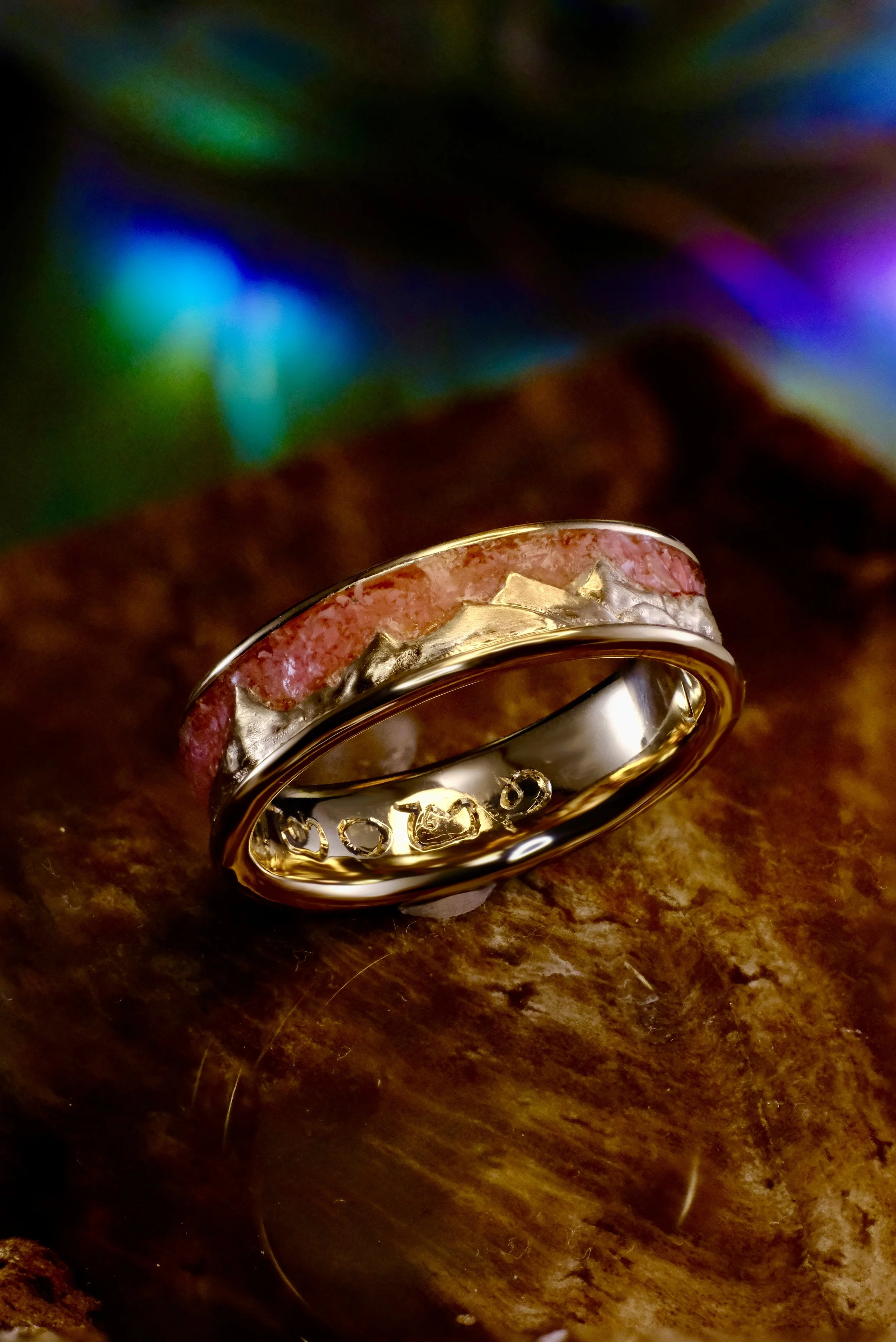 Yellow gold band with pink opal inlay encircling the ring, with raised mountain-style metal texture.