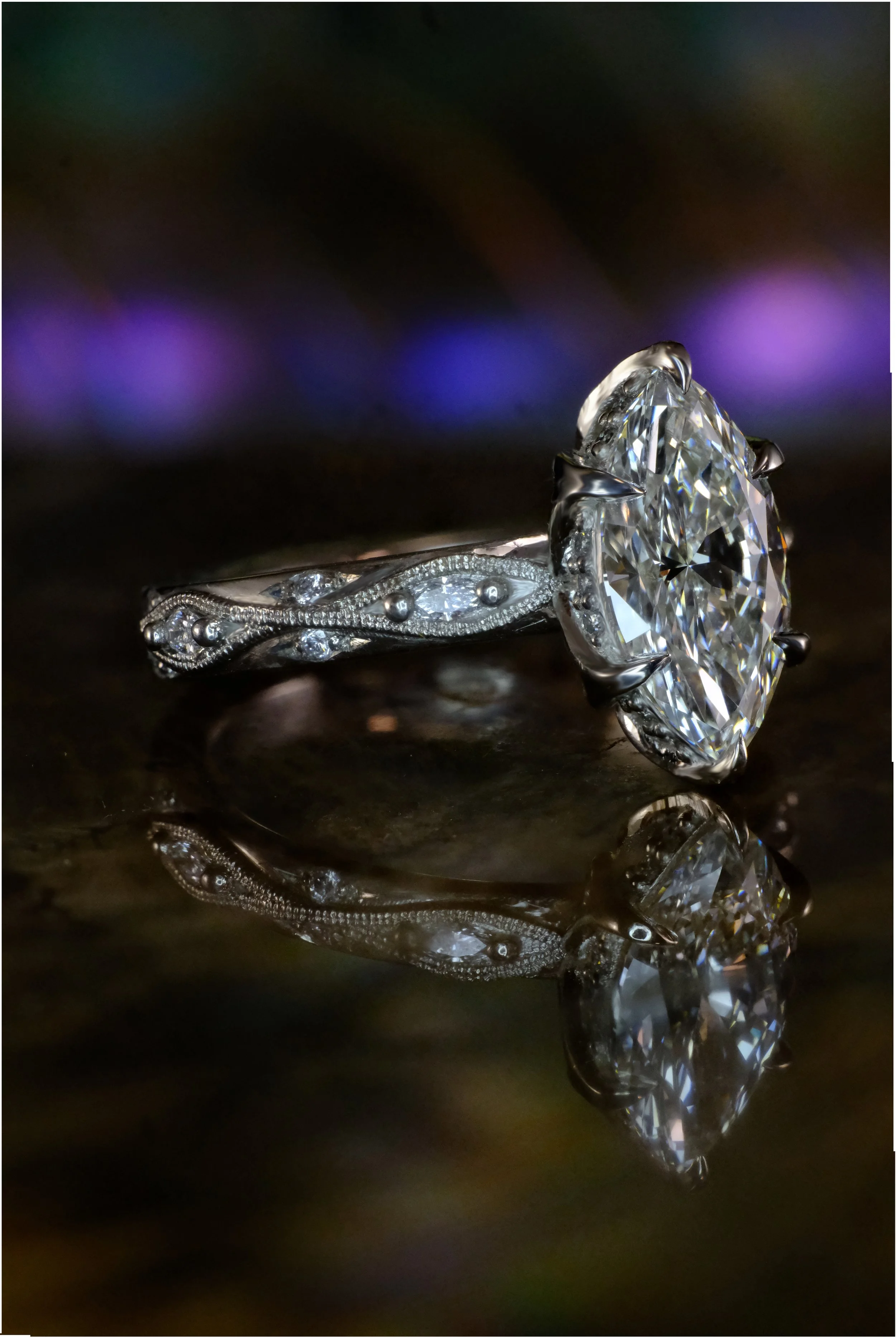 White metal ring with marquise diamond, shown from the side with prong setting and detailed band with small accent diamonds.