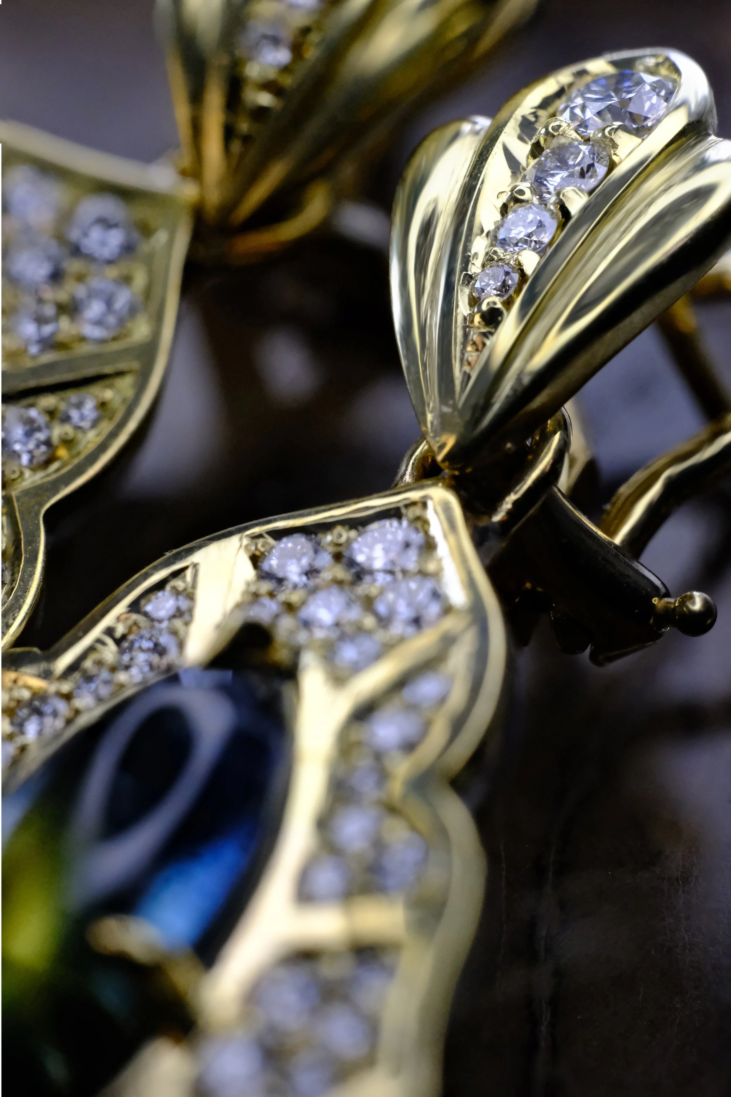 Close-up of yellow gold earring top with channel-set diamonds and part of the diamond-accented leaf frame below.