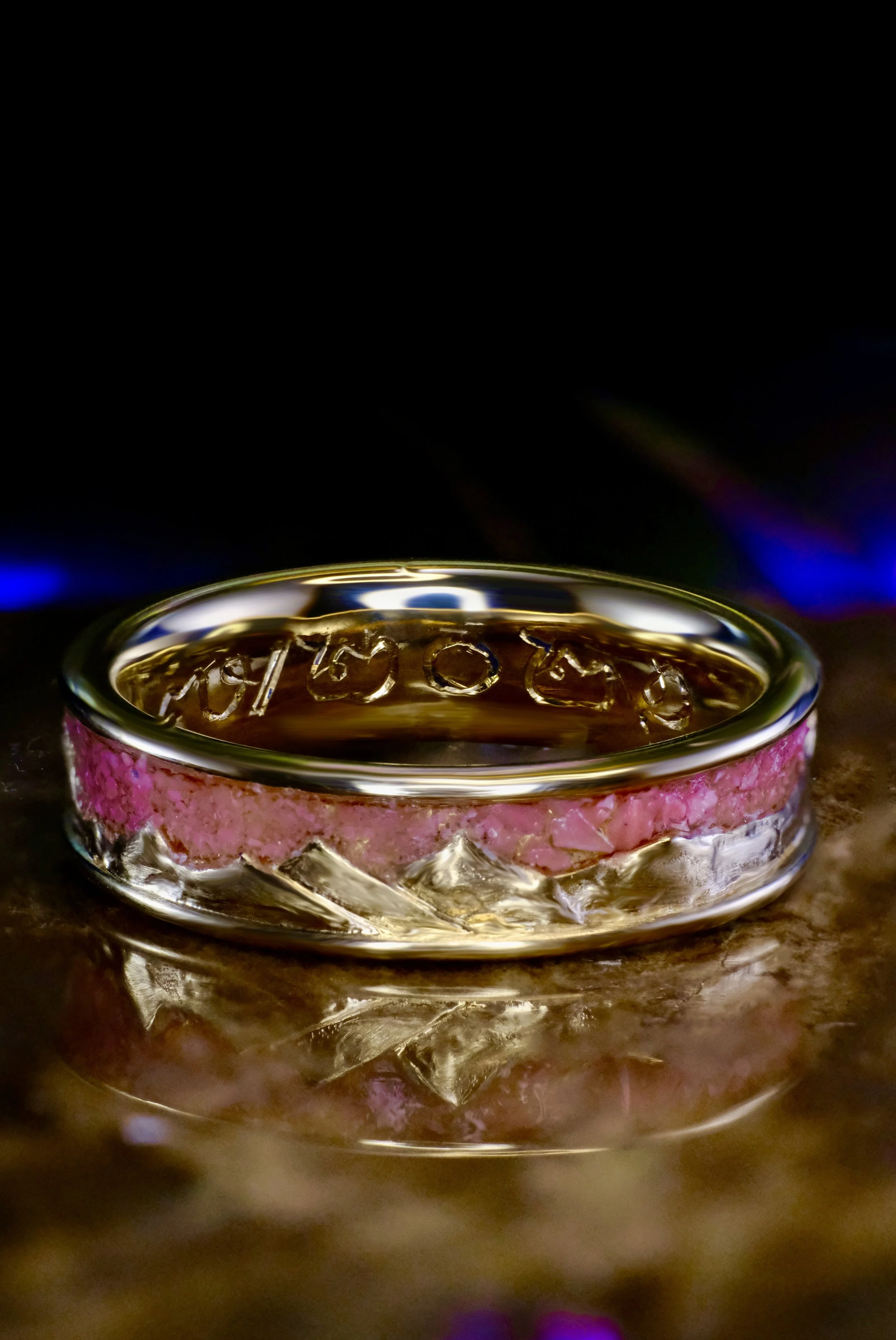 Yellow gold band with pink opal inlay encircling the ring, with raised mountain-style metal texture.