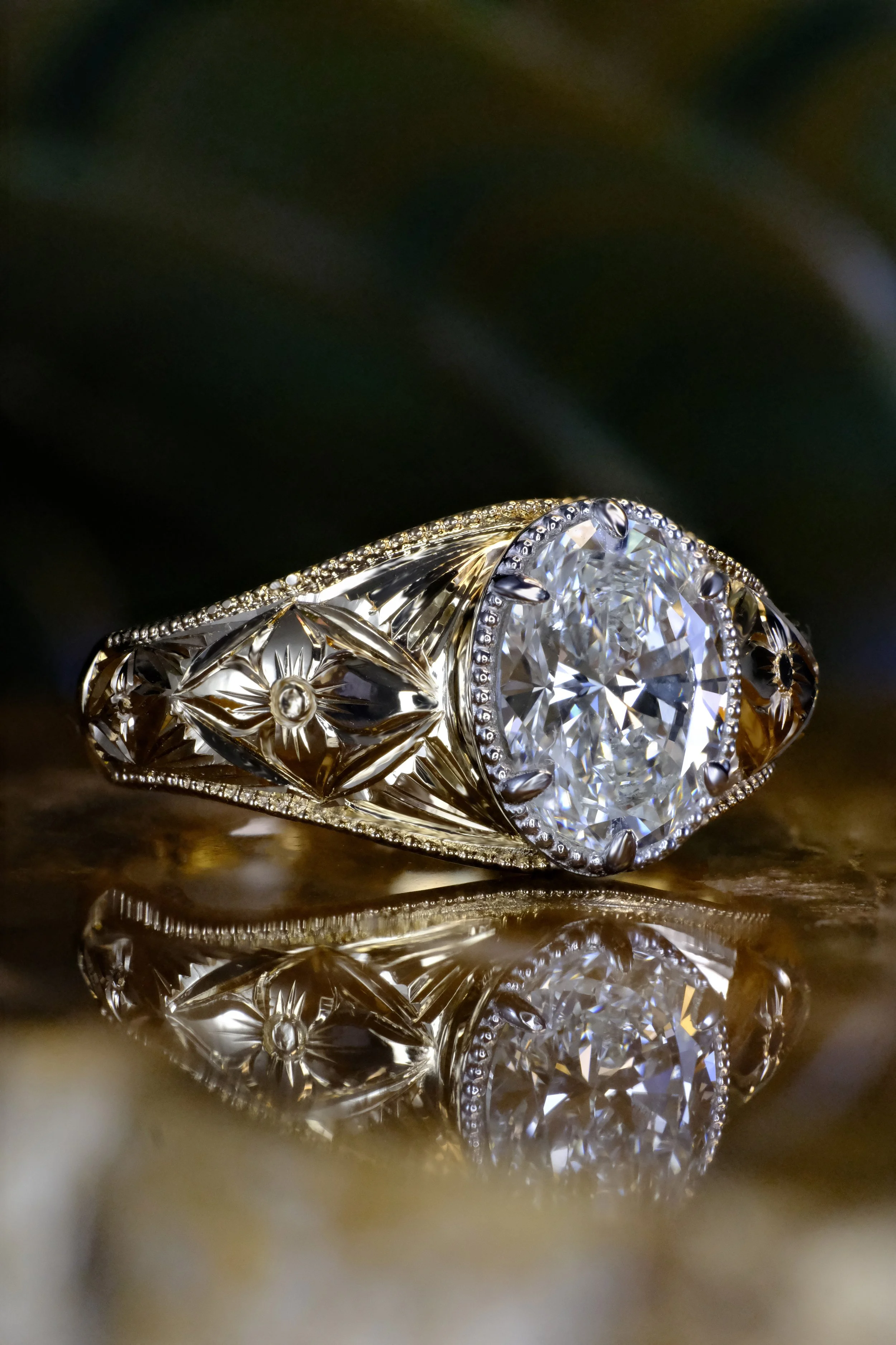 Yellow gold ring with oval diamond and engraved band, shown from the side highlighting detailed carving and setting.